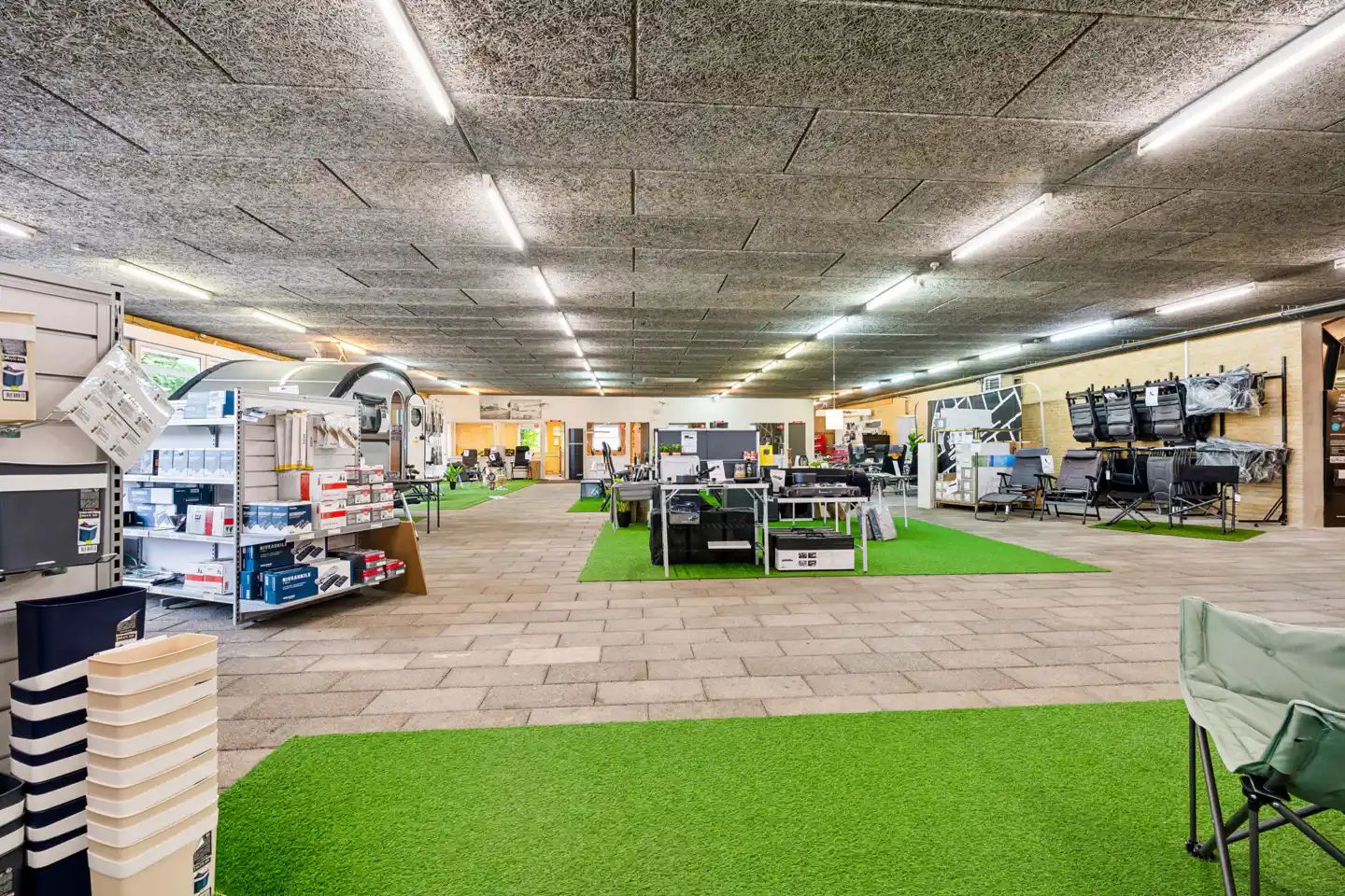 Lejemål med campingvogne og campingudstyr udenfor. Lejemålet har flere udstillingsområder med campingstolene og