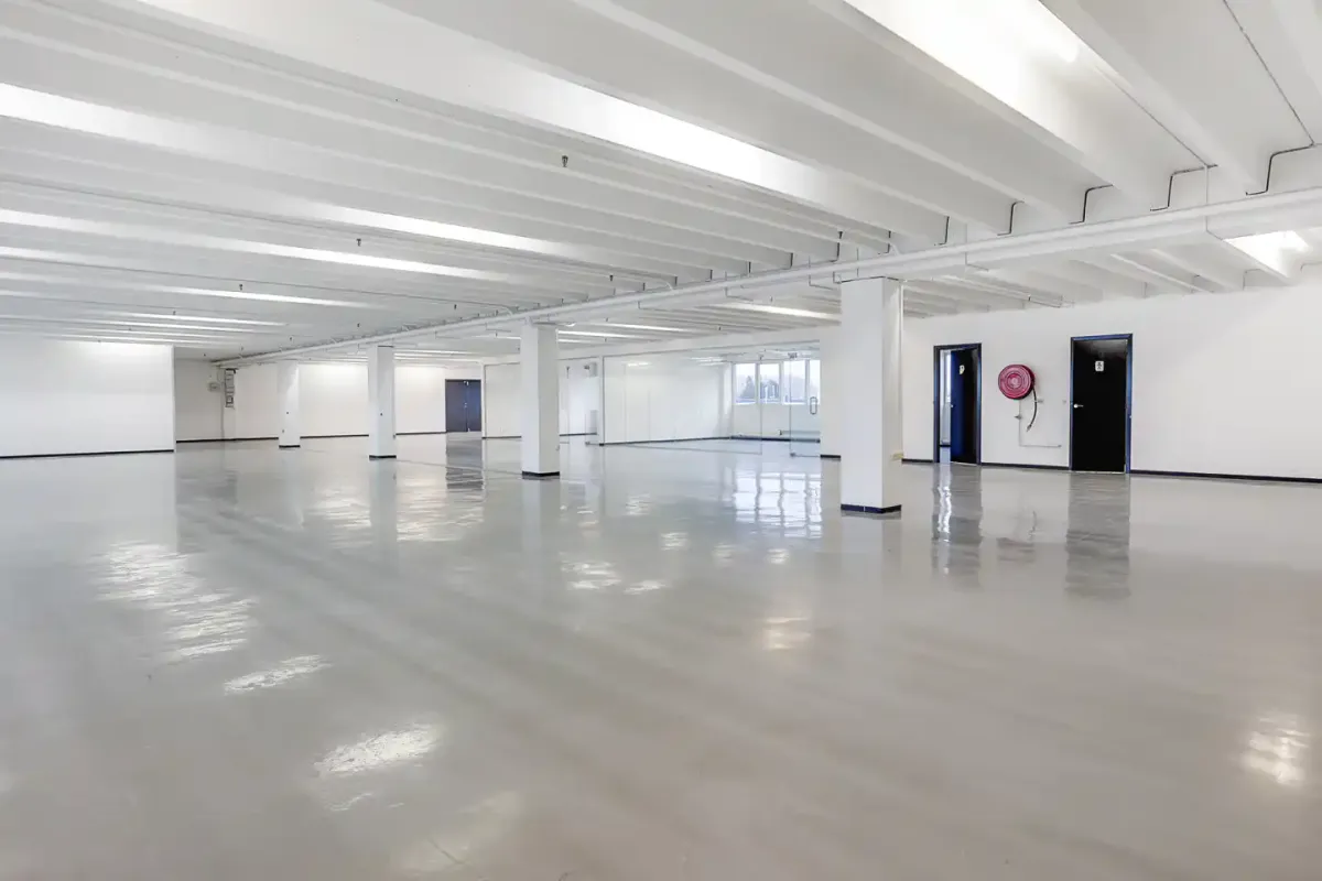 En stor hall med hvide vægge og lofter, lyse gulv og tæt tæt afstand mellem søjler og døre