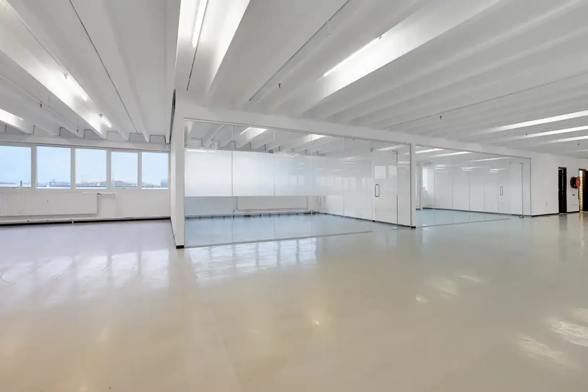Et stort kontorlokal med hvide vægge, højt til loftet og glasvægge og døre