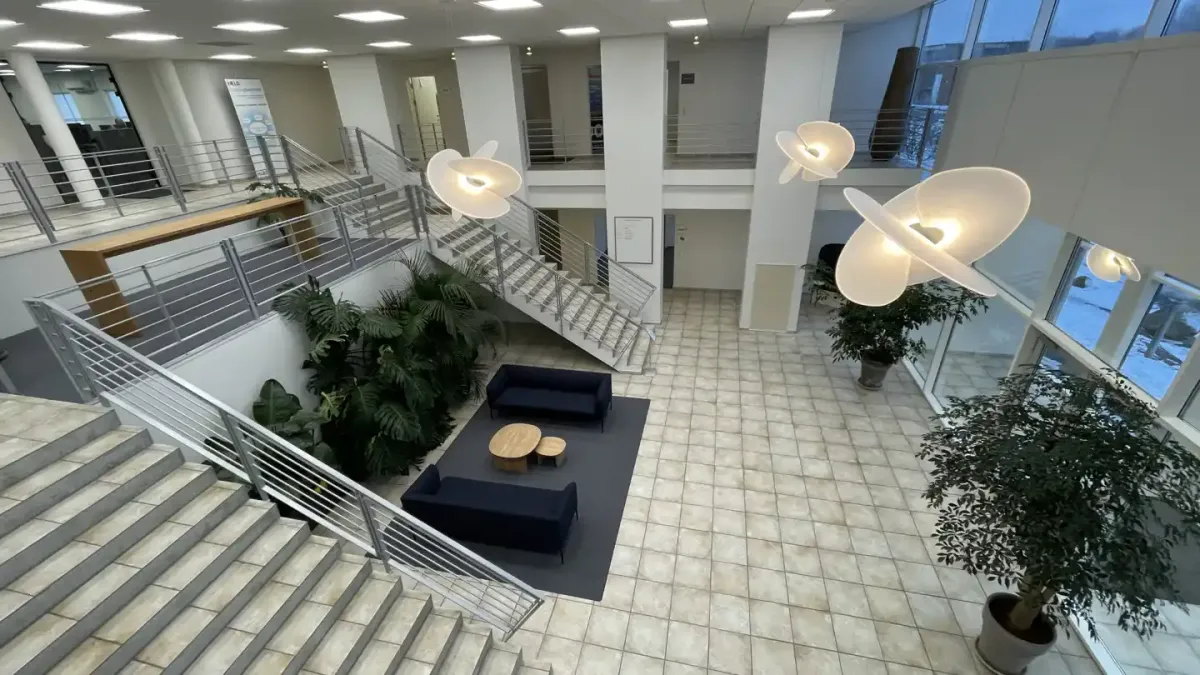 Moderne lobby med hvide møbler og lyse gulvfliser samt lysekroner i loftet og grønne planter