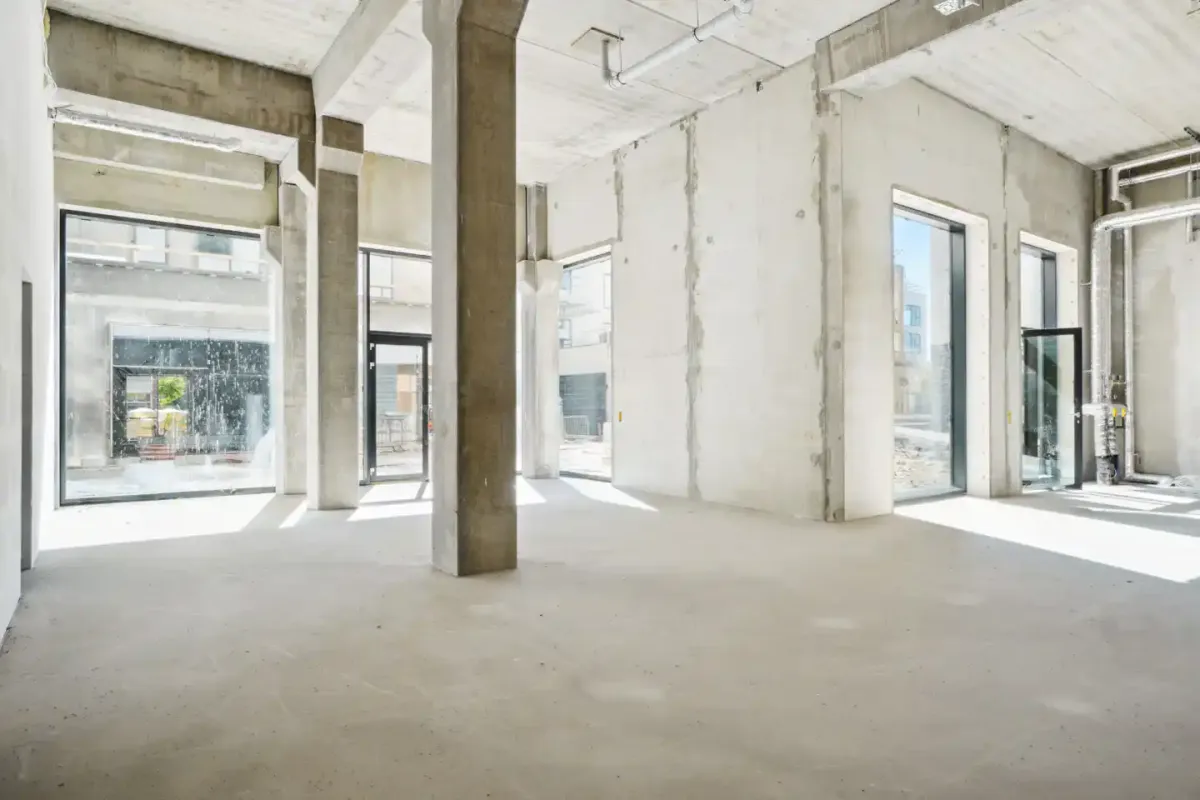 En stor, tom og hvid malet lokale med højt til loftet, store vinduer og to stærke søjler i midten