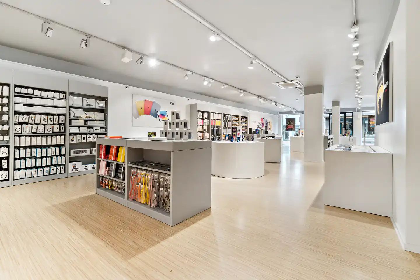 Inde i et højteknologisk butikslokal med møbler og hylder, udstillet produkter og indbygget belysning, og et lyse loft med