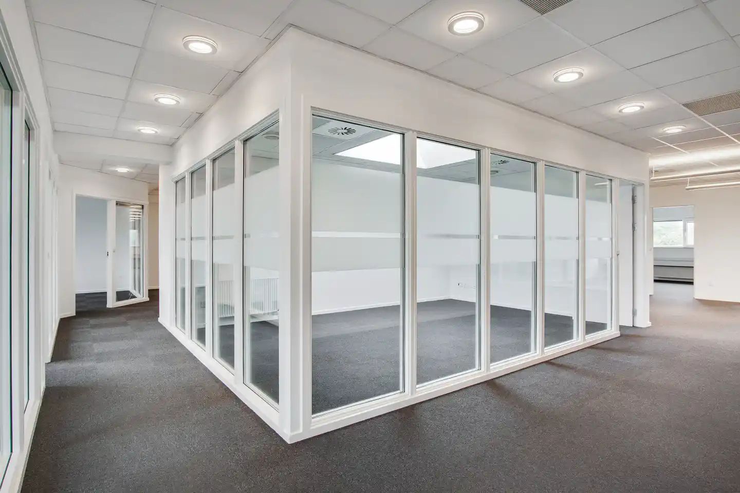 Kontorbygning med hvide vægge og glasvinduer. Et stort glasparti og store, hvide vægge. Ingen møbler og ingen mennesker.