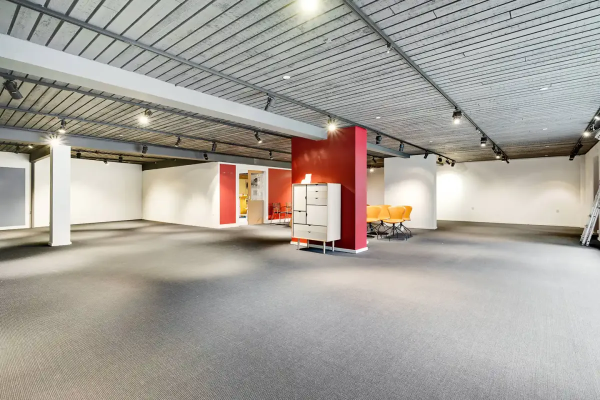 Ledig lokale med loft, vægge og gulv i hvid og rødt og møbler og lysarmatur i gul og rød farve