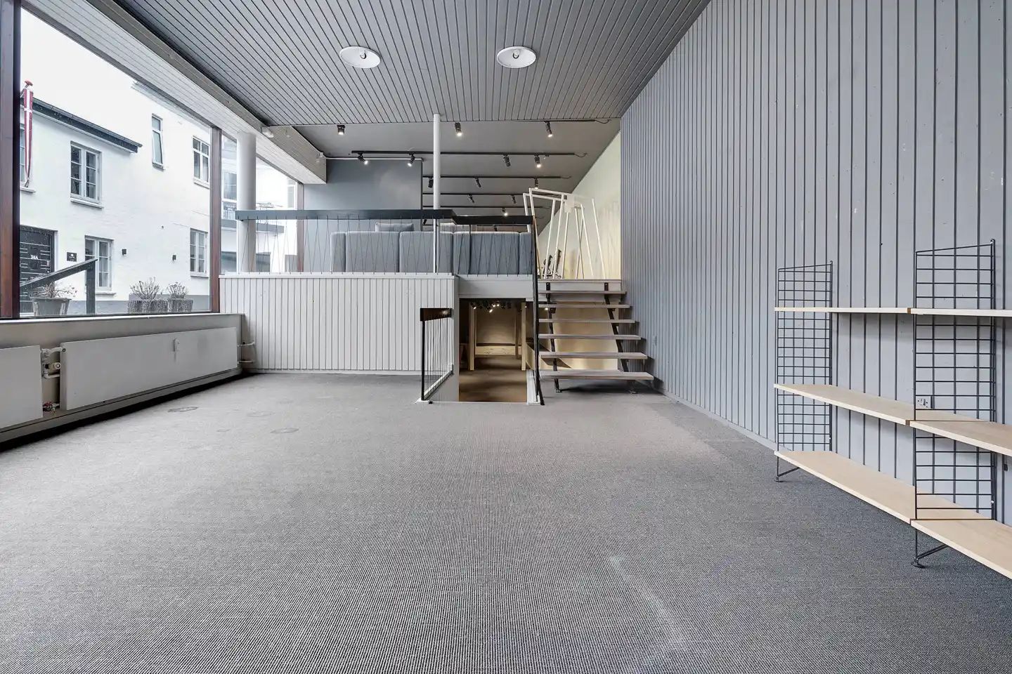 Store rum med lyse lofter og gulvbelægning, ligesom der er en trappe op til et højre niveau og et håndtag på en dør