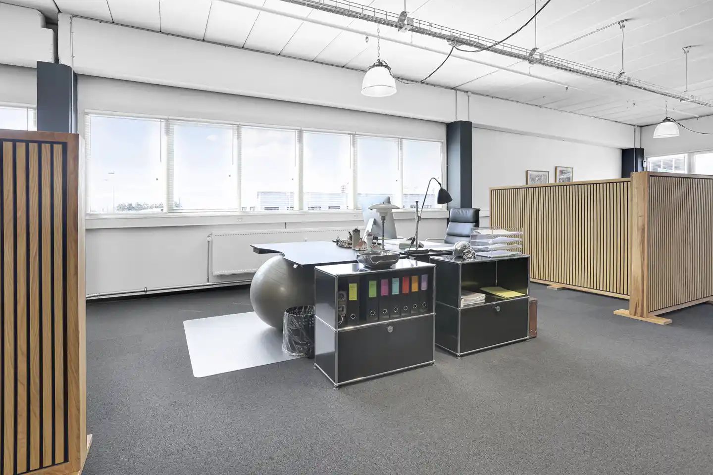 Et kontor med lyse lofter, vinduer, stol, skrivebord, lamper og loftsvinduer. Et loft med lysepunkter og ledninger. Et gulv