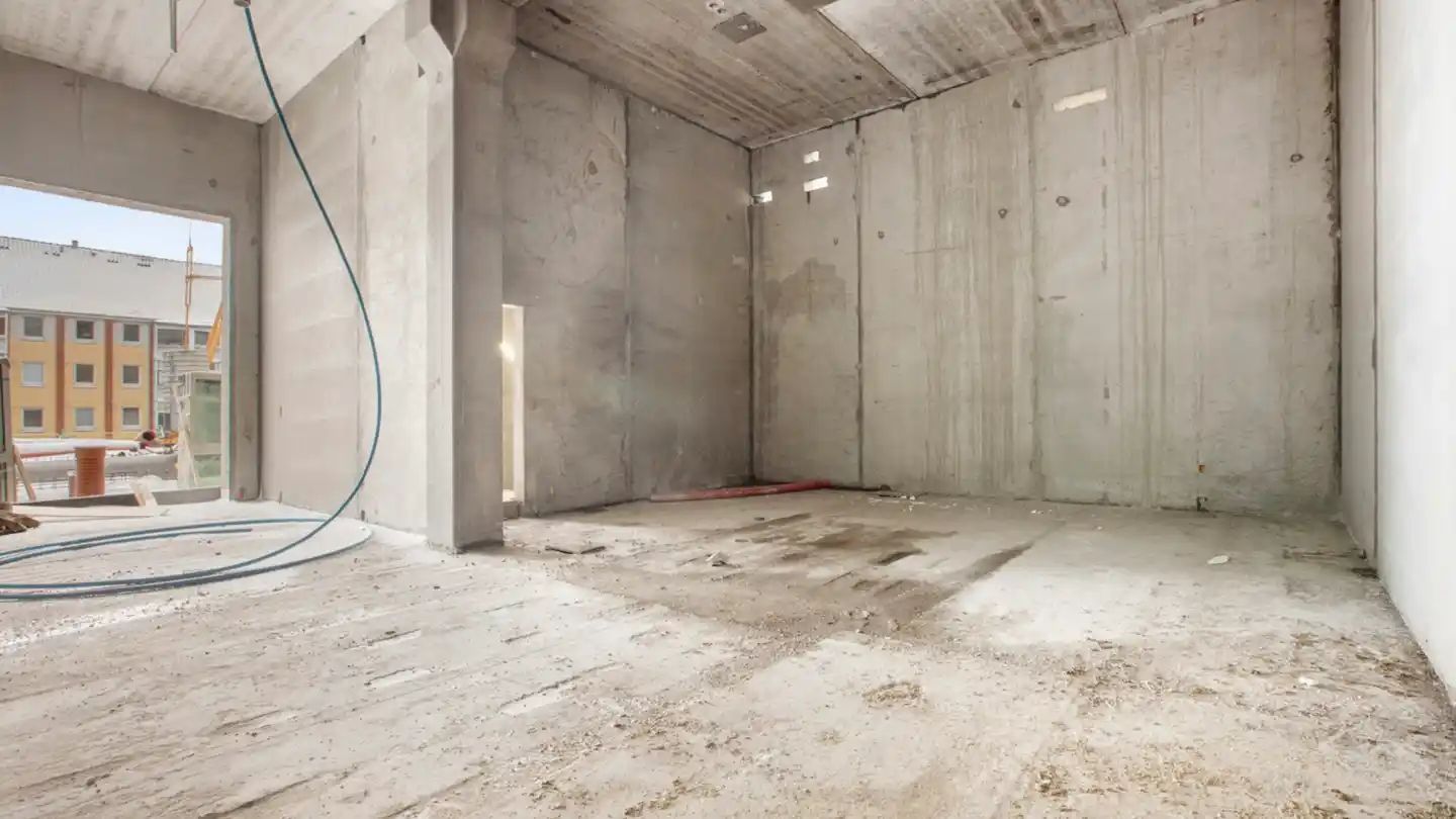 Et byggeprojekt i fuld gang med høje vægge og gulv, tomme rum og støv overalt