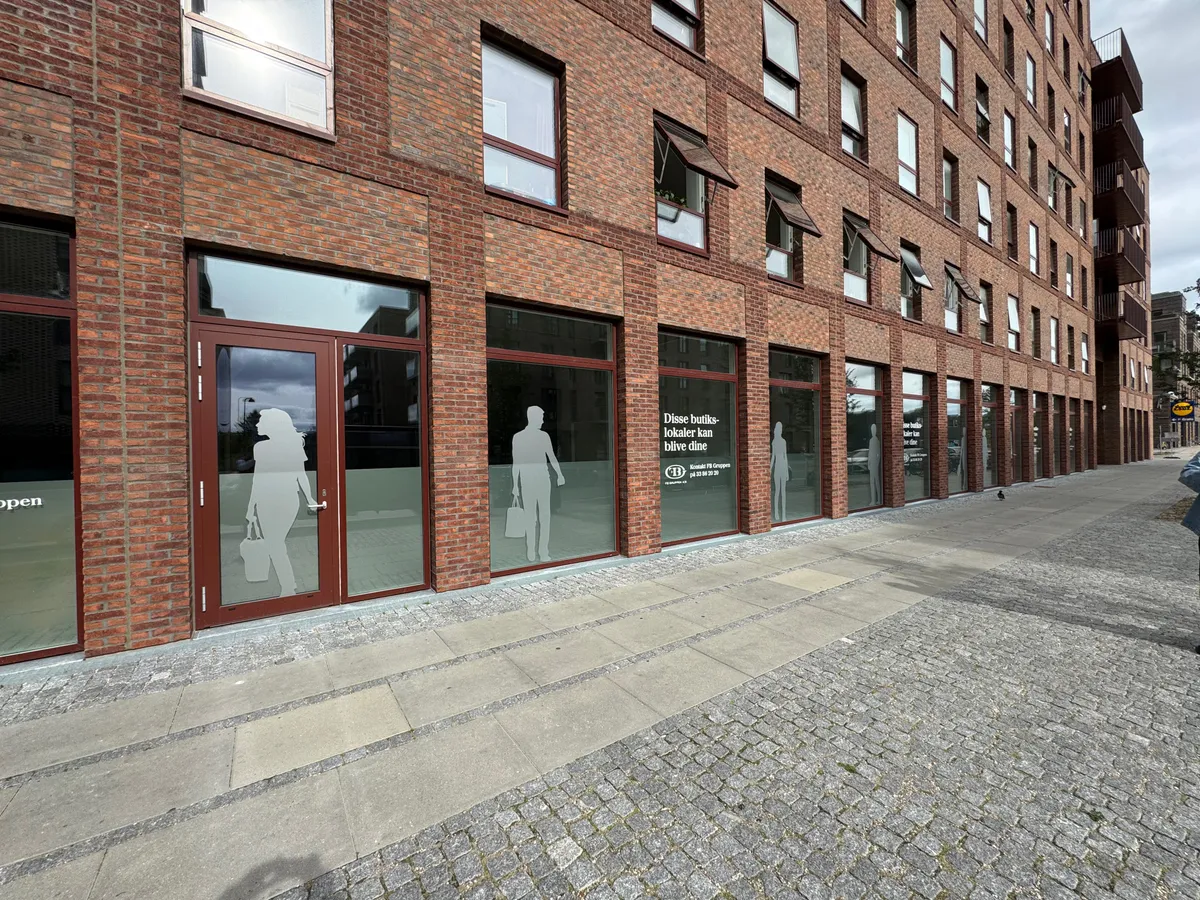 Lejemål på Grønttorvet i Valby. Lokal kan lejes til butik, møbler inkluderet. Butikken har glasruder og røde døre.