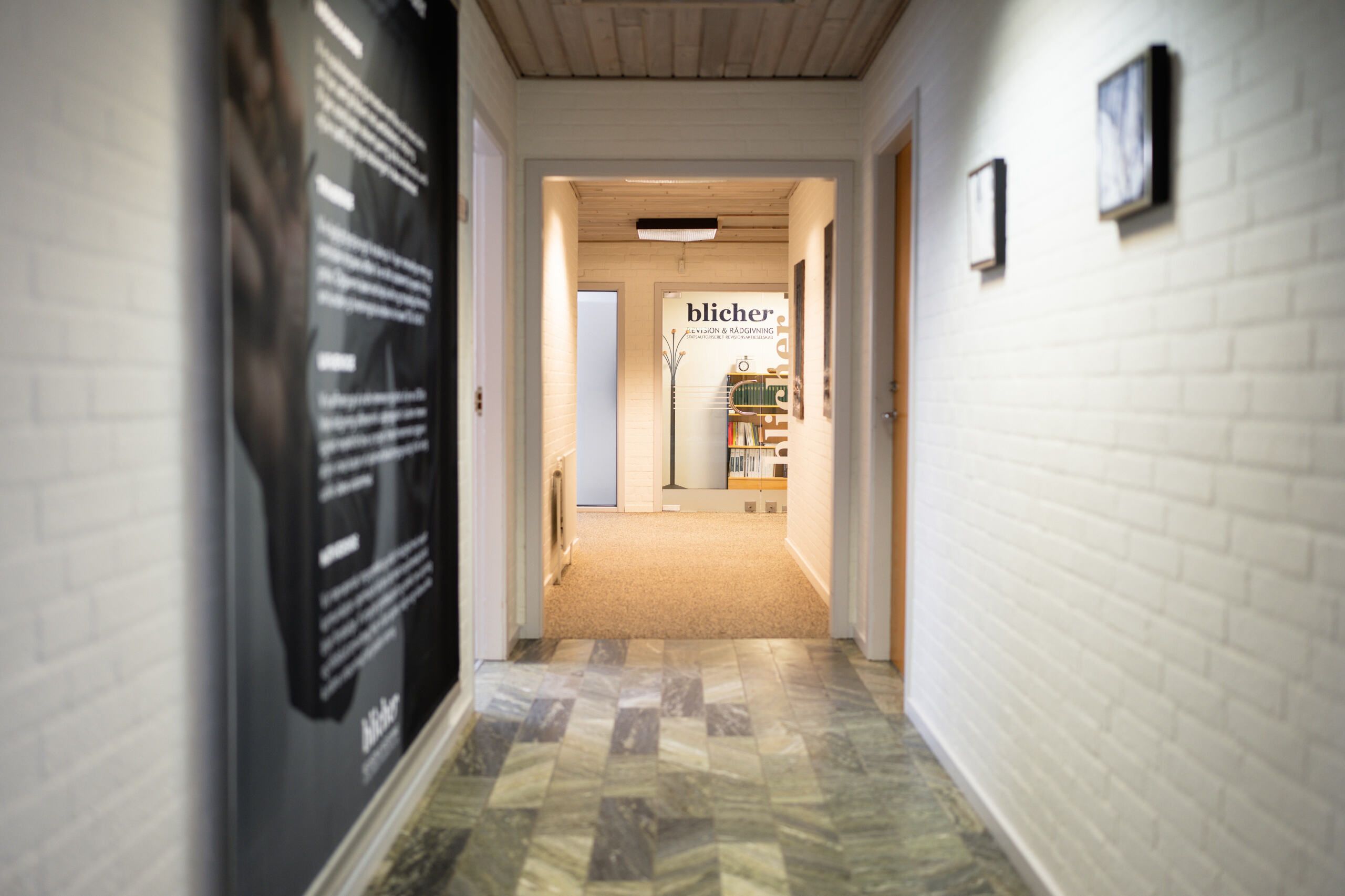 En indgangshal med marmorgulv, hvid krydsfinerbelagt væg og skrift på væggen