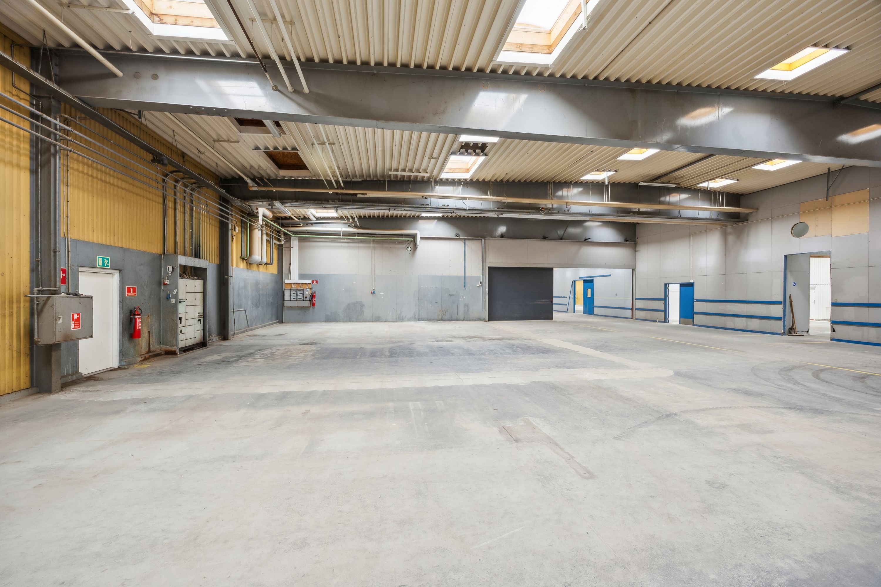 Lager med lagerrum og døre. Ingen mennesker og gulv og loft med mange vinduer og loftsrum.