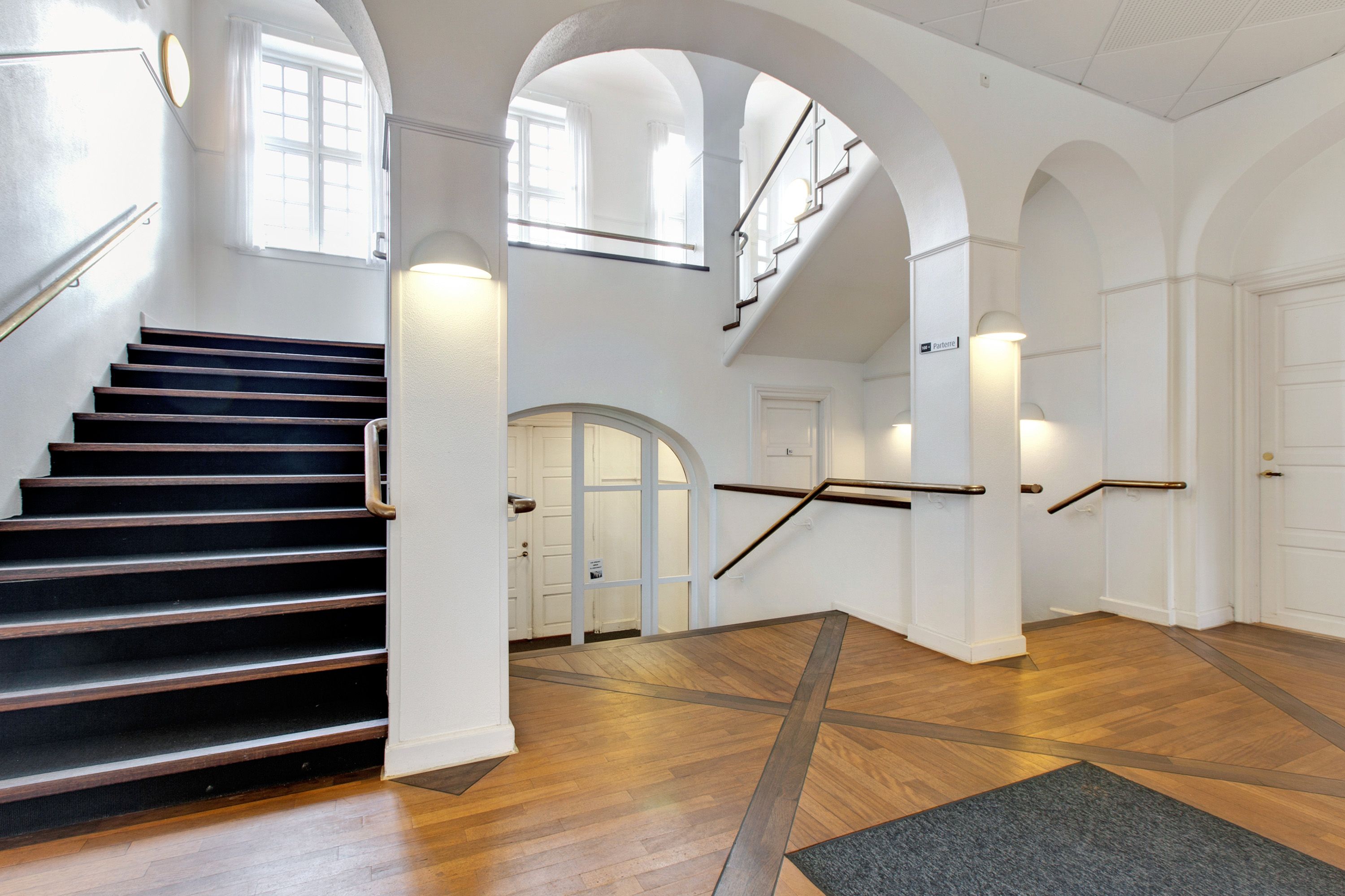 Inde i MERCUR på Haderslevvej i Kolding, ser vi en marmorgulv og hvide vægge med to trapper, hvor den ene fører til en dør