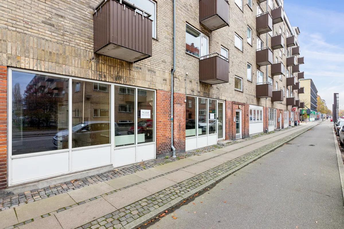 Lejlighedsbygning med terrasser og glasvinduer på Holmbladsgade. Lejlighederne har vindue og balkon. Et køretøj er