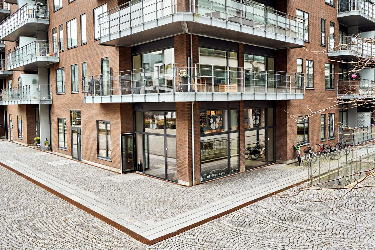 Moderne lejlighedsbygning med terrasser og glasvinduer og en række cykler parkeret på siden af bygningen