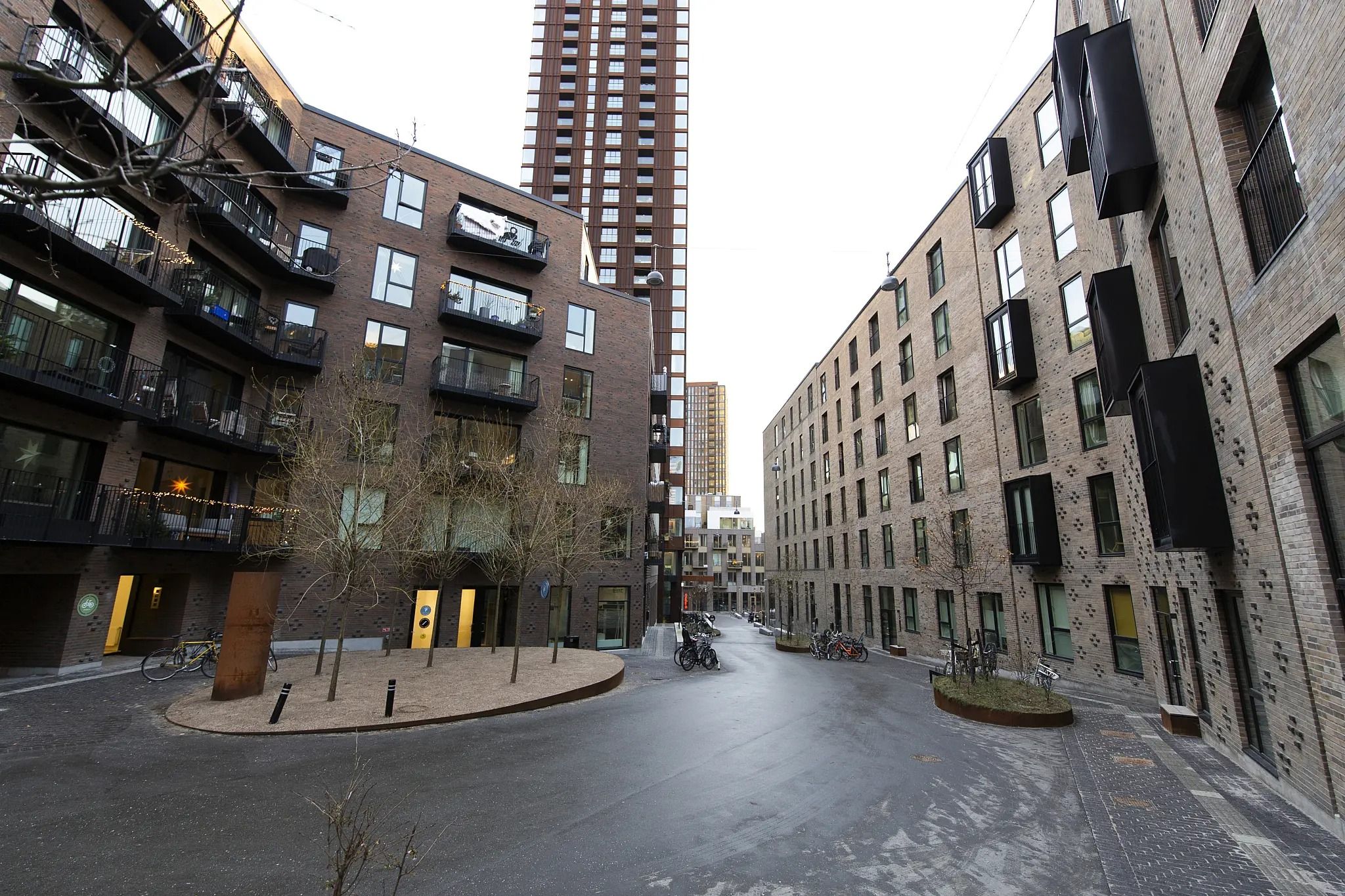 Byggedejendom med parkeringspladser og blomsterbed, der ledsages af skulpturer og småtræer