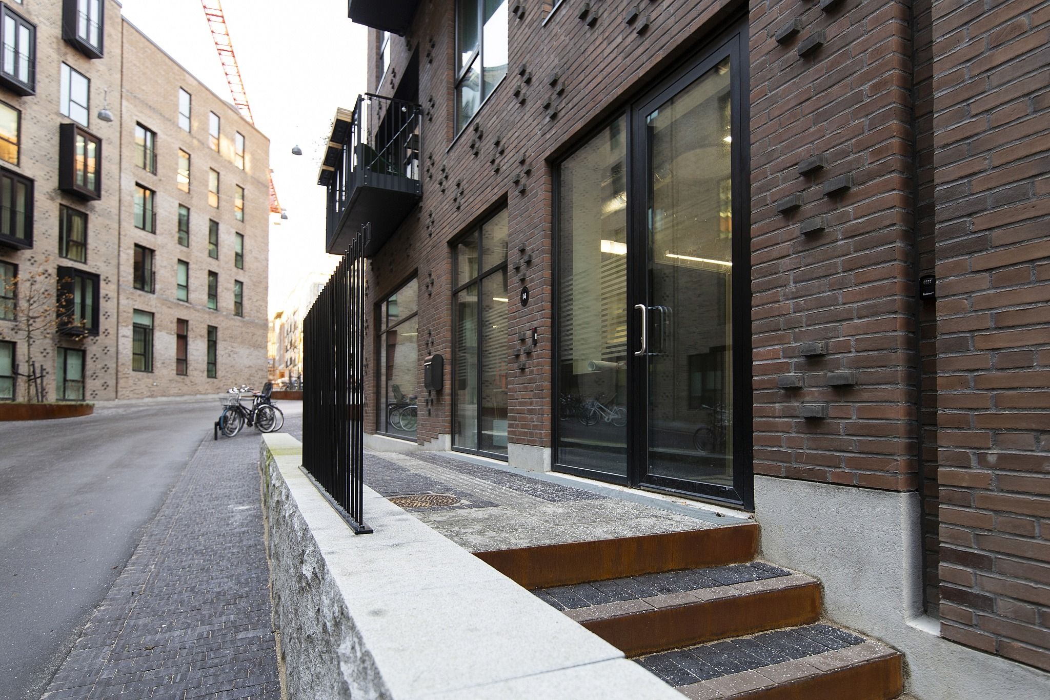 En nyopført gård med røde mursten og store glasruder ud til gaden. Stående trapper uden for hoveddøren.