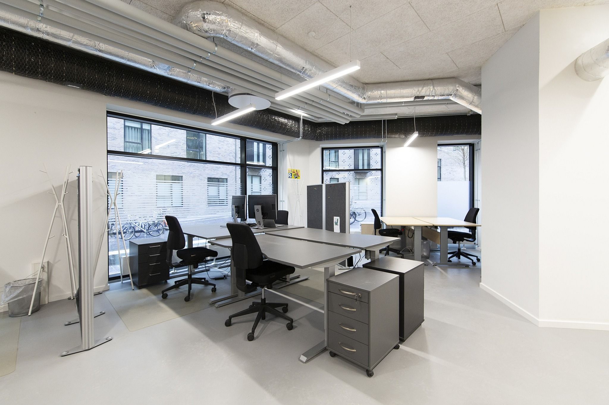 Moderne kontor med lyse loftslampe, skriveborde og højkvalitets kontormøbler med computere og lyse vinduer