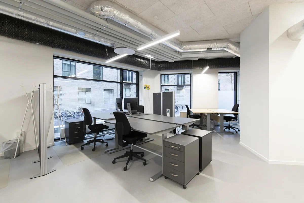 Moderne kontor med lyse loftslampe, skriveborde og højkvalitets kontormøbler med computere og lyse vinduer