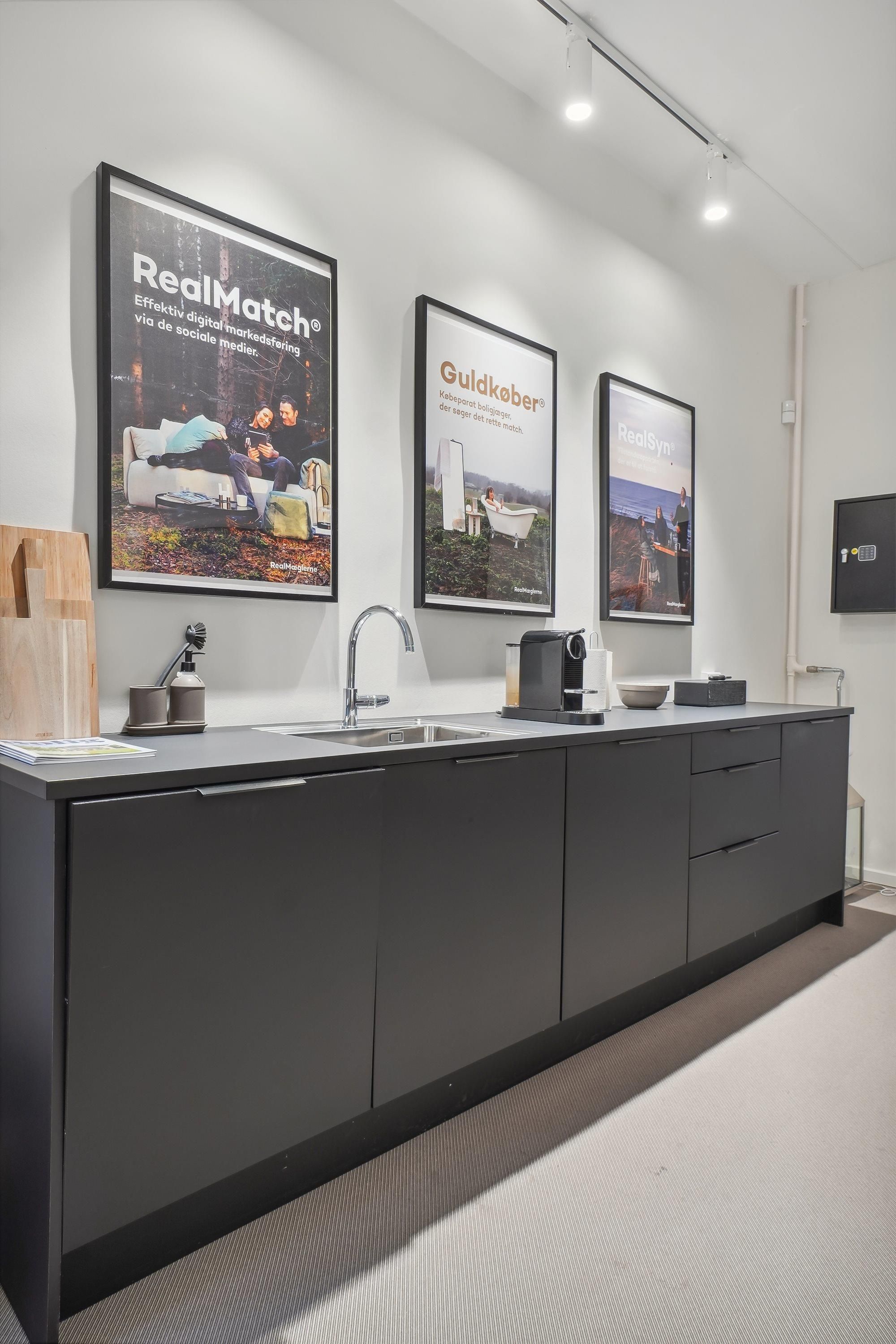 Foto med et moderne køkken med møbler og plakater, gulv og lofter samt udstyret køkken med vandhaner og kogeapparater