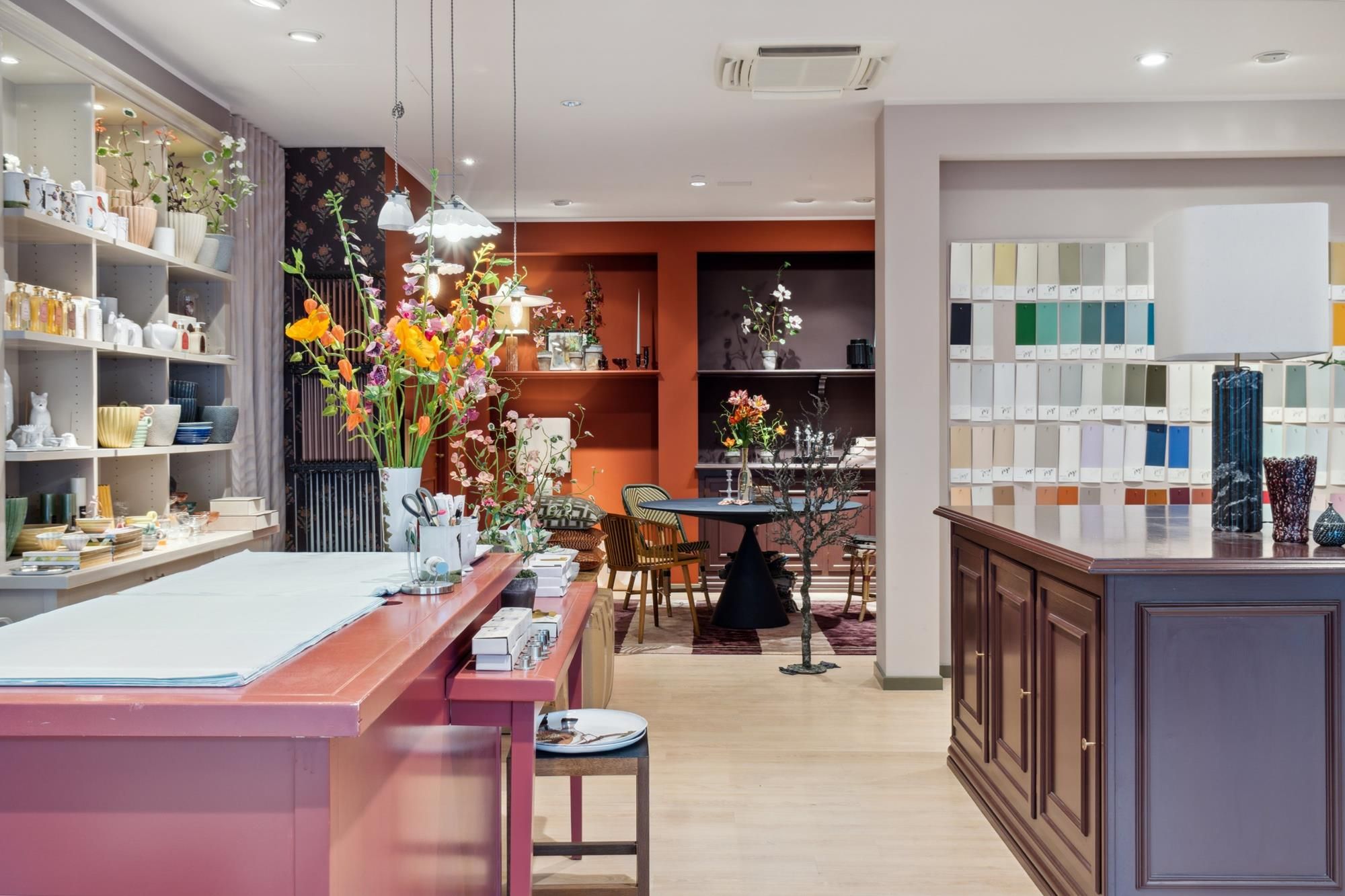 Forretningslokal med hyggeligt og kunstnerisk indretning, smukt oplyst med lysekroner og plantearrangementer, og hyggeligt