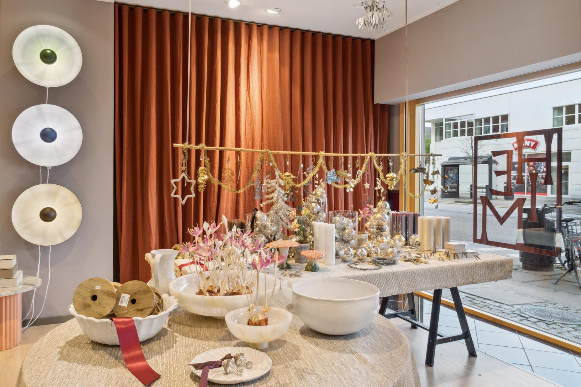 Elegante indretning med hvide skåle og messinglamper, forskellige pyntegenstande og møbler langs væggen og i det åbne område