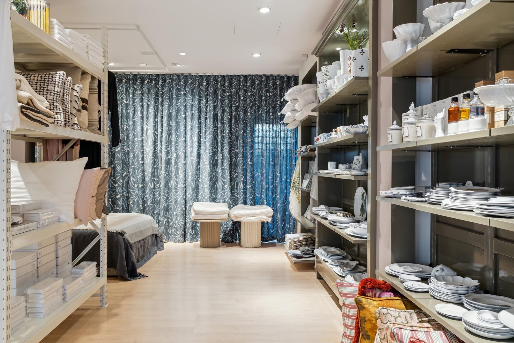 Lyst og veludstyret detaillejemål med mange tæpper, tøj og køkkenudstyr på hylder og på gulvet