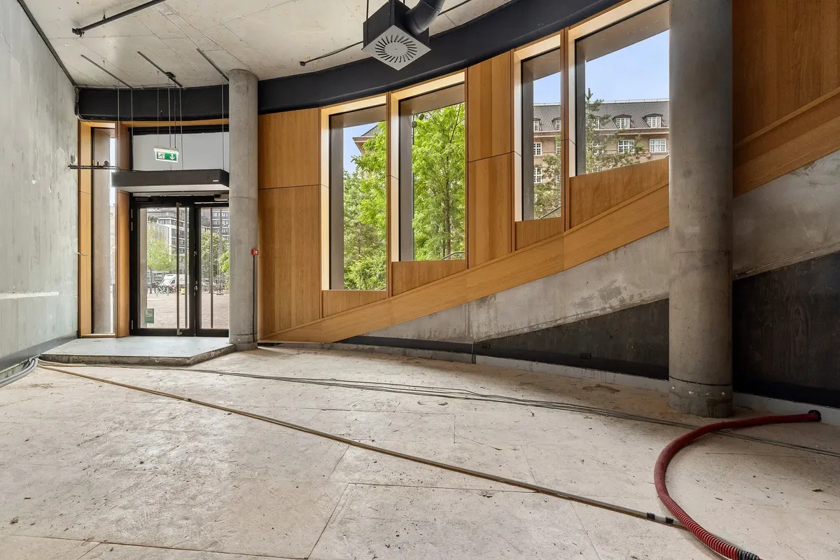 Dobbeltglasdør og vinduer i en møbleret indgangshal med lyse gulve og rødt slangemateriale