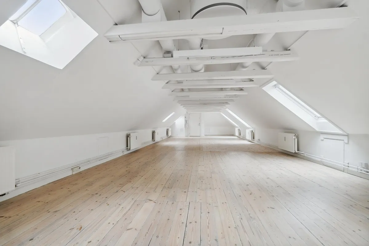 En ren, stor og luksuriøs kontorplads med lyse lofter og lysegulve, udstyret med hvide radiatorer og vinduer med udsigt til