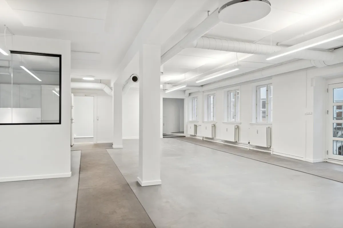 Ledig og nyrenoveret kontor i lyse farver med højt loft og store vinduer