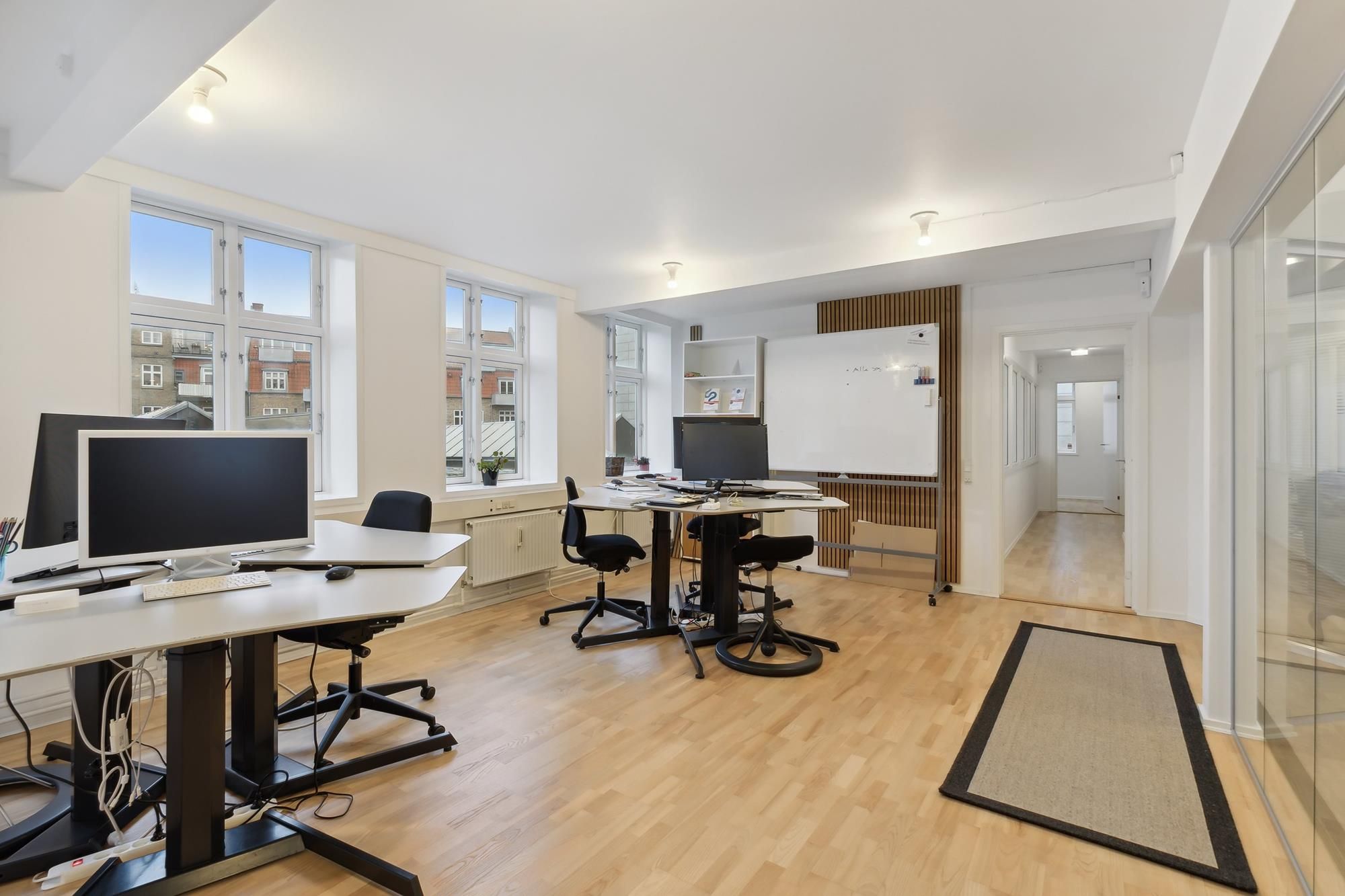 Moderne kontor med højt til loftet, store vinduer og minimalistisk indretning med højttalere og skriveborde