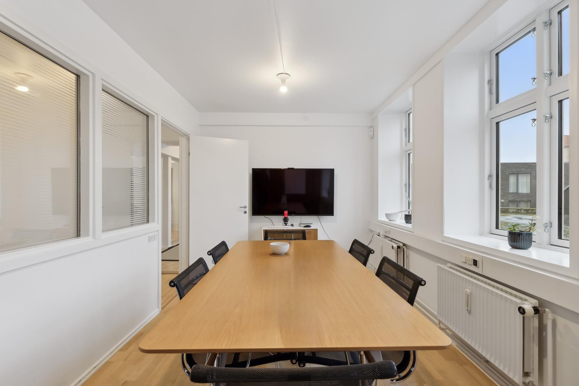 Moderne kontor med lyst gulv, store vinduer og en lækker lang borde med stole