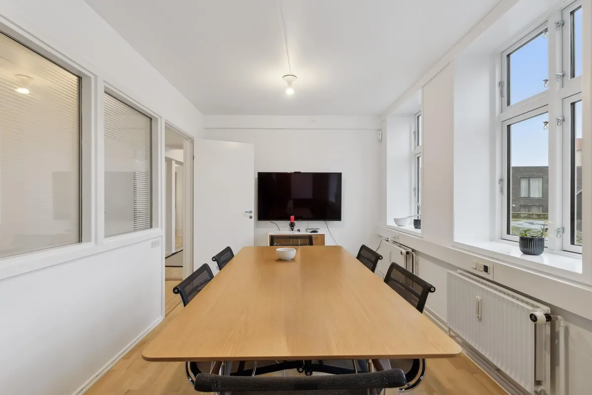 Moderne kontor med lyst gulv, store vinduer og en lækker lang borde med stole