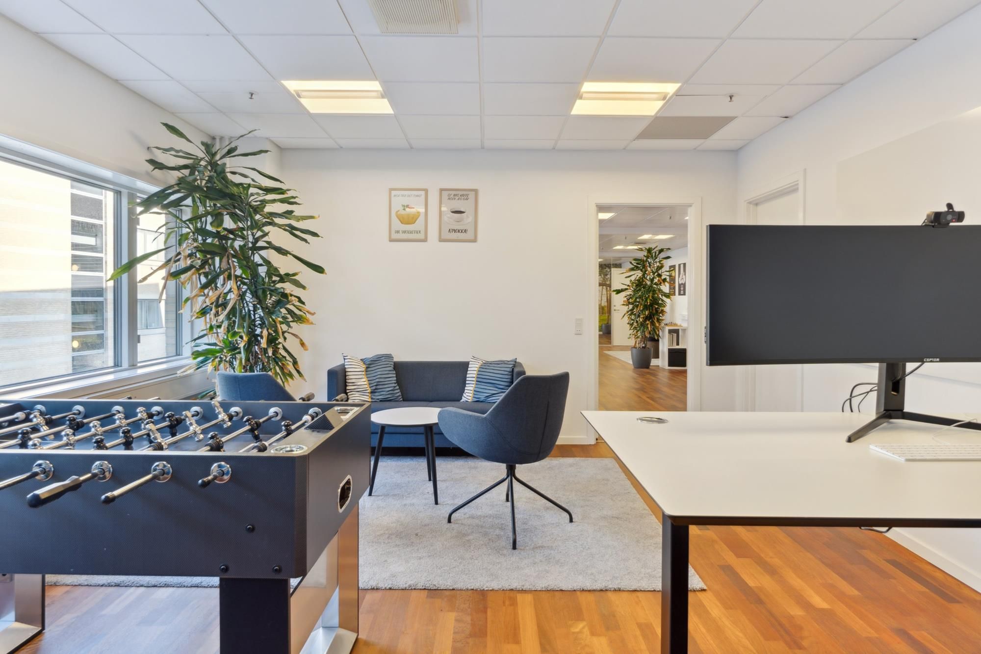 Det moderne kontor med en fuldt udstyret arbejdsstation og en stor fodboldbord samt flere myggeplanter og møbler til at