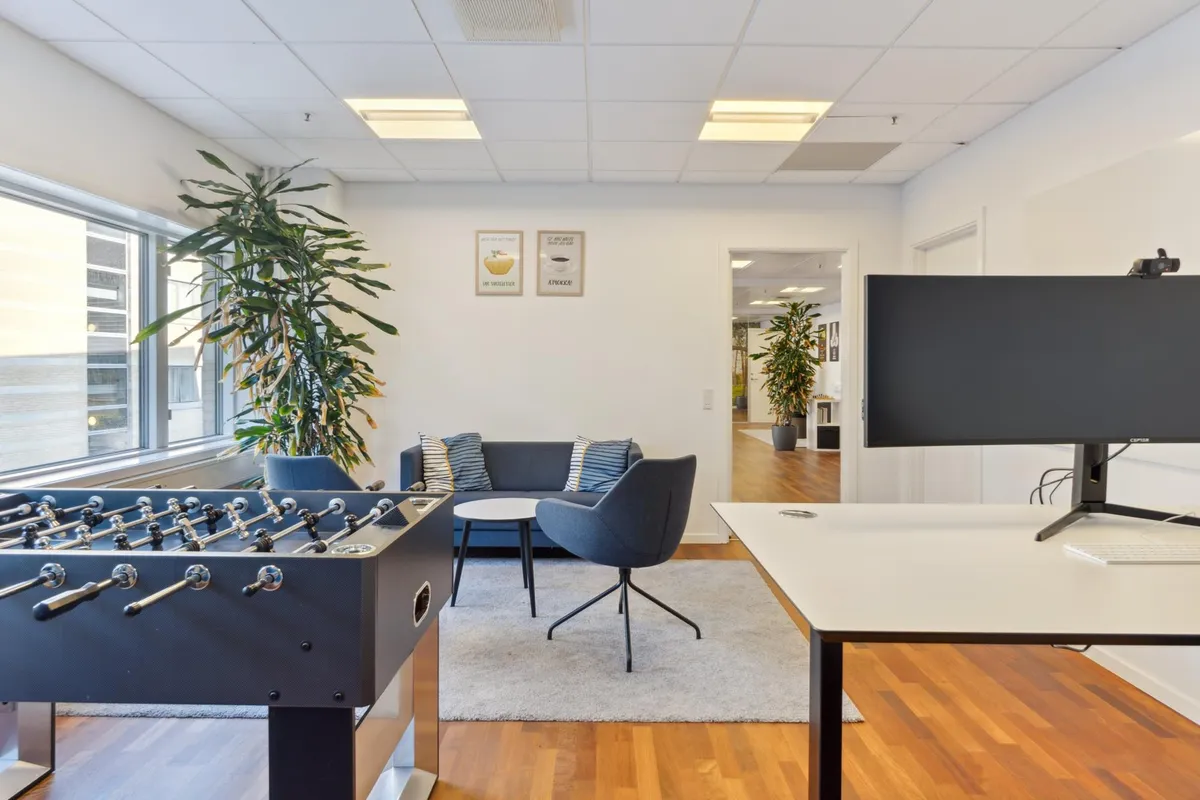 Det moderne kontor med en fuldt udstyret arbejdsstation og en stor fodboldbord samt flere myggeplanter og møbler til at