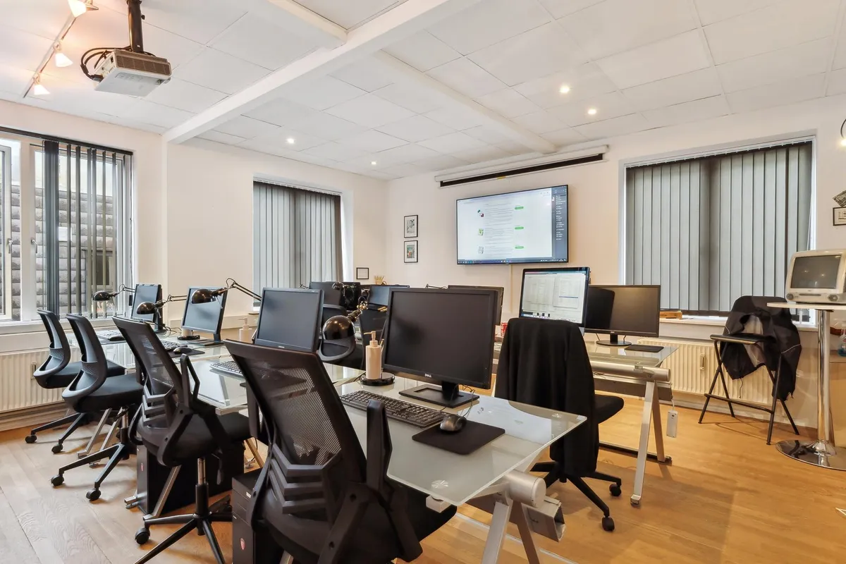 Lejet er udstyret med skriveborde, stålstole, skærme, en projektor og en stor computermonitor i højre side af rummet