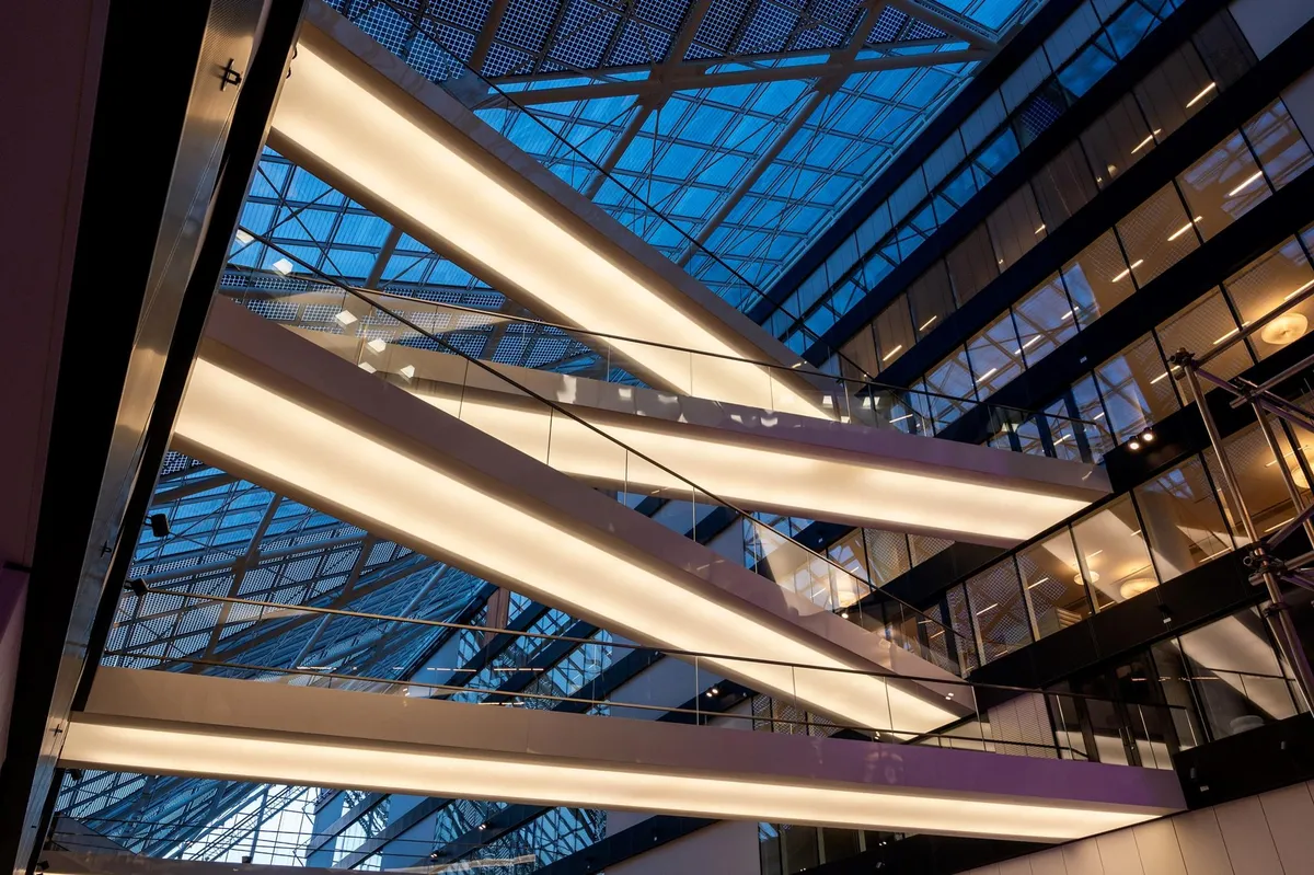 Glasloft med metalstrukturer, lyse rør og glasbalanger, glasvinduer og refleksioner af lys og bygning i loftet