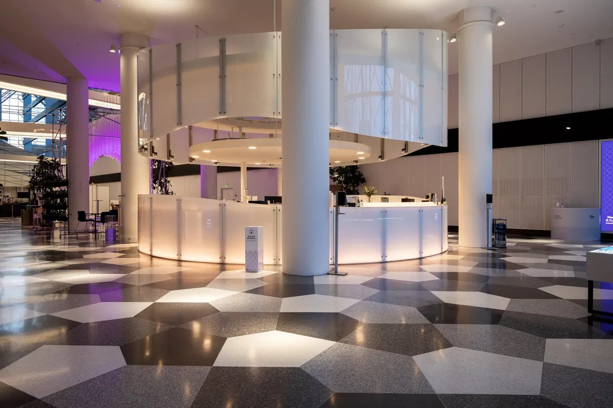 Moderne lobby med marmorgulve og hvide møbler, store glaselementer og lysekroner, samt en stor, rund reception med glas og