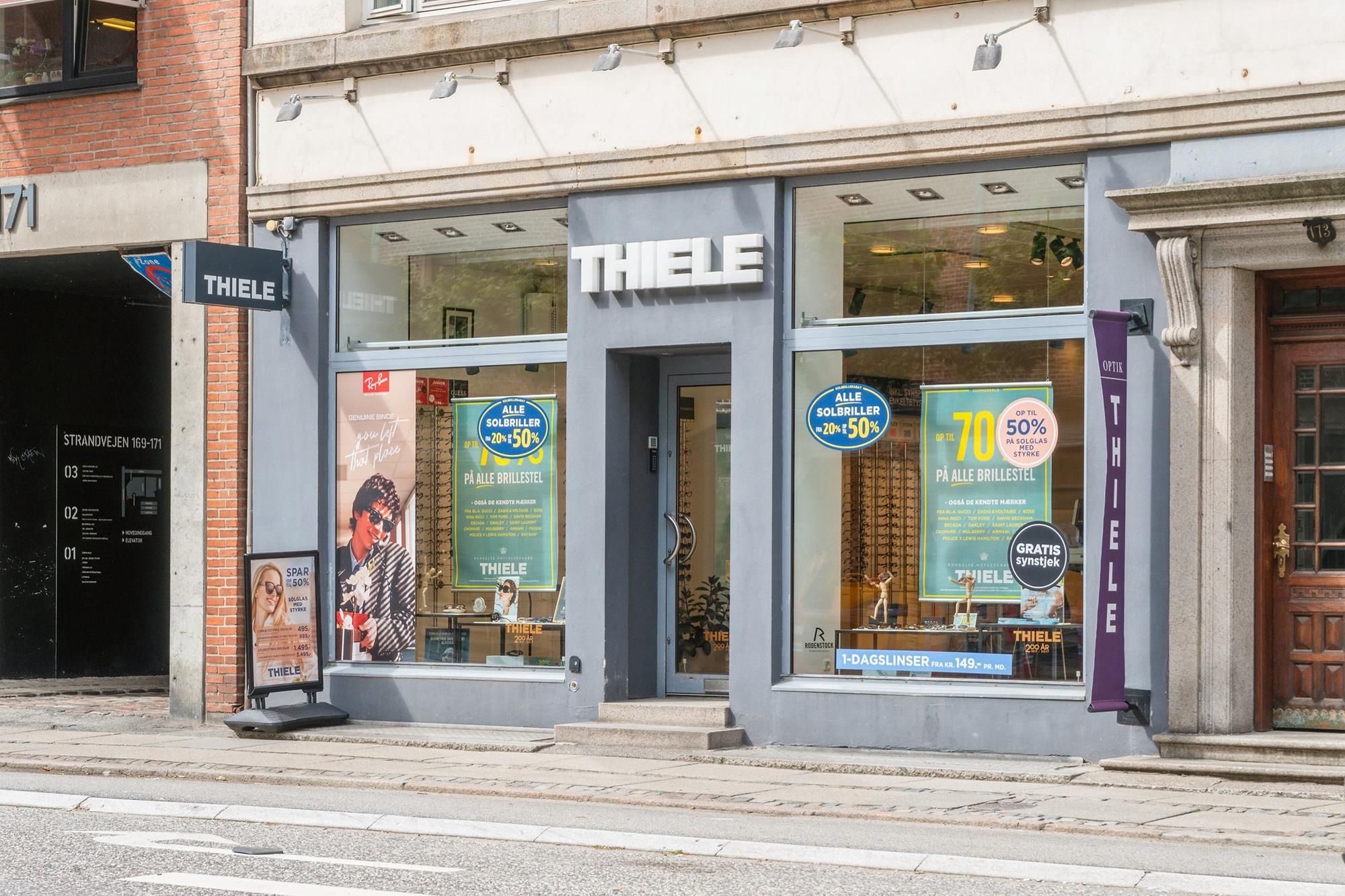 Thiele brilleforretning med rabatvisning og reklame på glasvinduet og en stolthedsskilt på vejsiderne