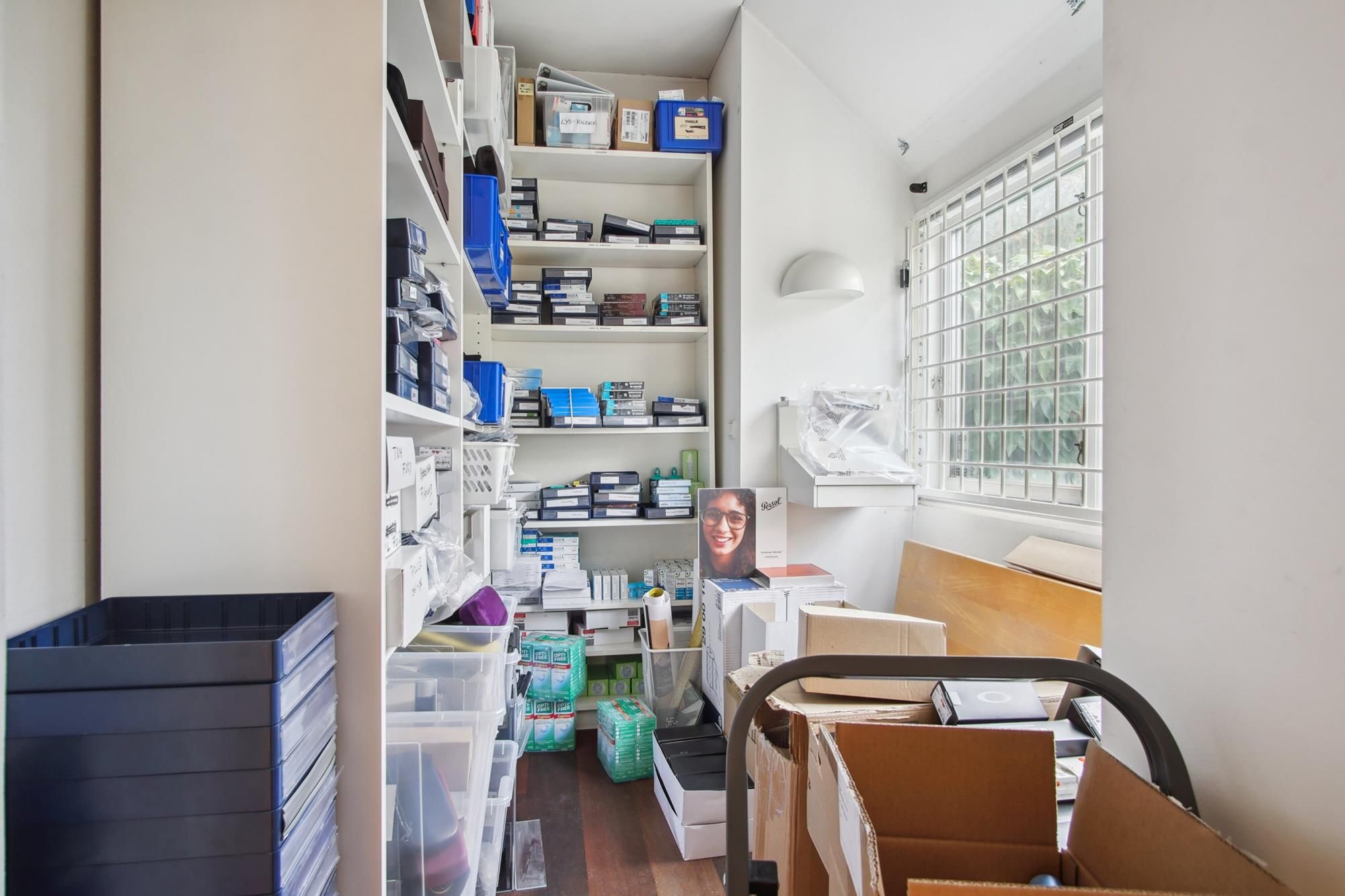 Sorte plastikbakker og kasser samt et stativ med en person i et lager med forskellige produkter og emballager