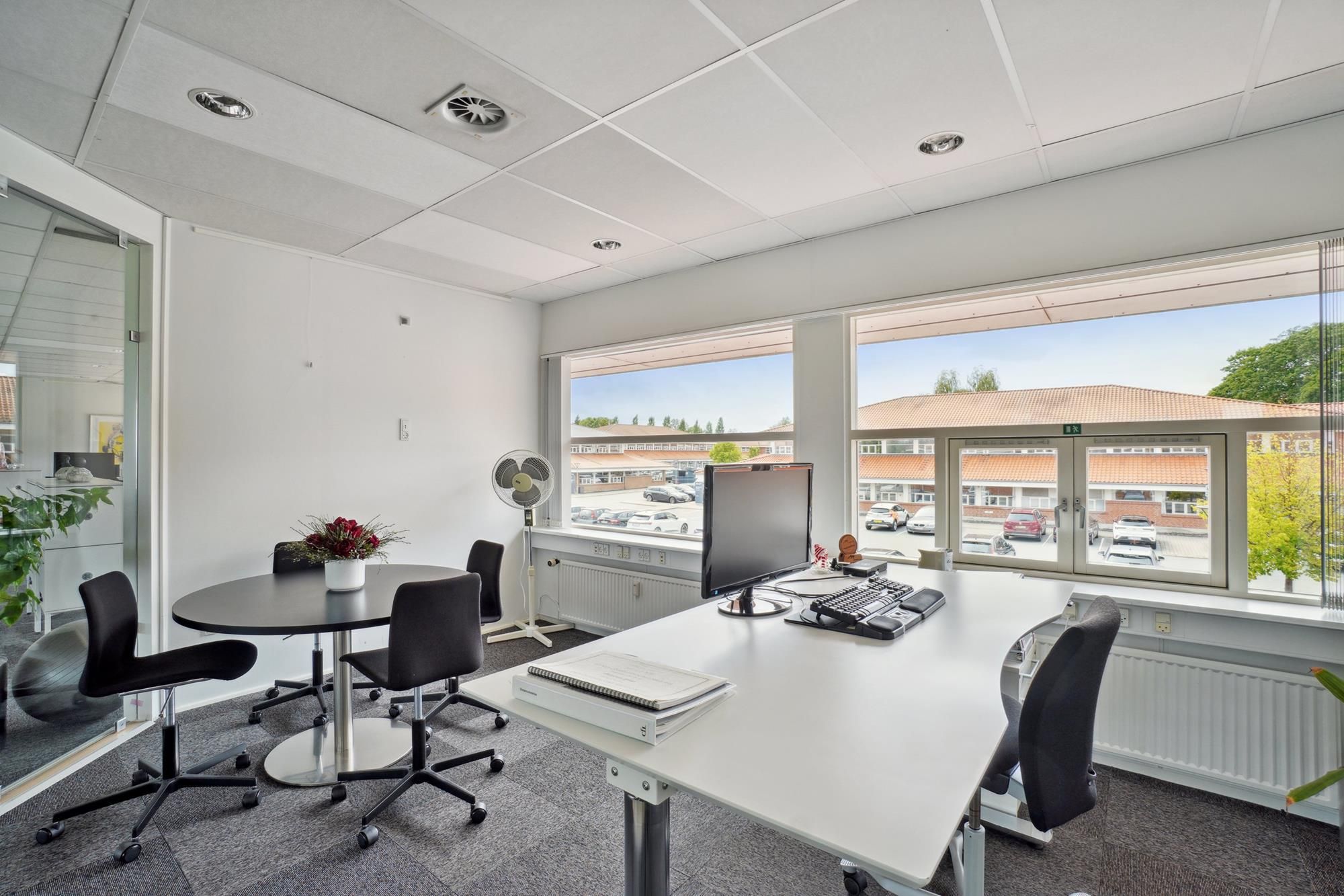 Moderne kontor med møbler og udsigt til parkeringsplads med biler og bygninger