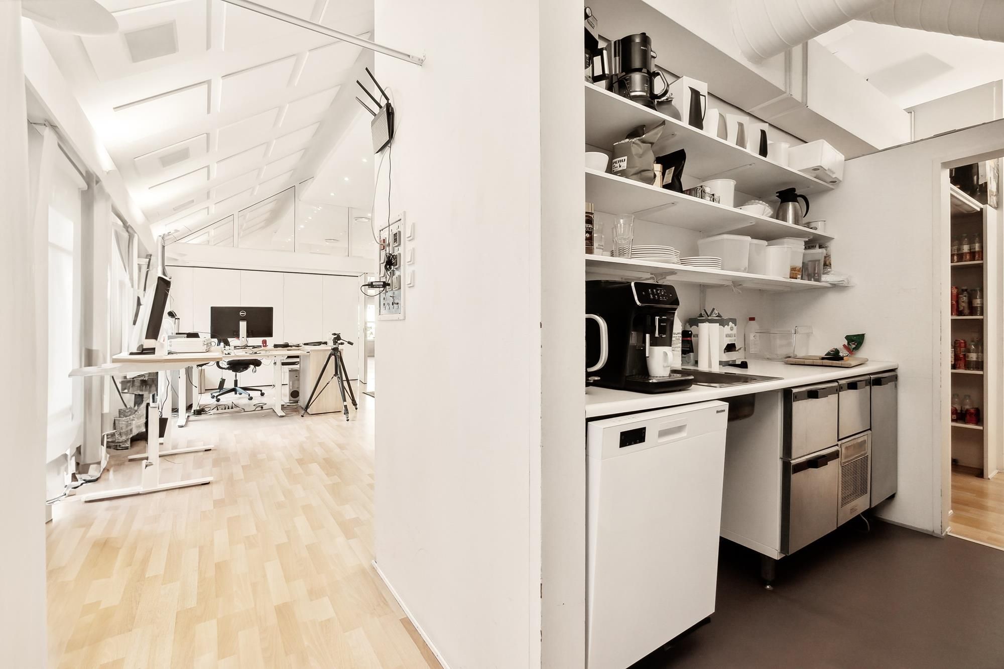 Højloftet kontor med højtliggende loft, højloftet køkken med lyse hjørner og moderne udstyret skrivebord med monitorer og