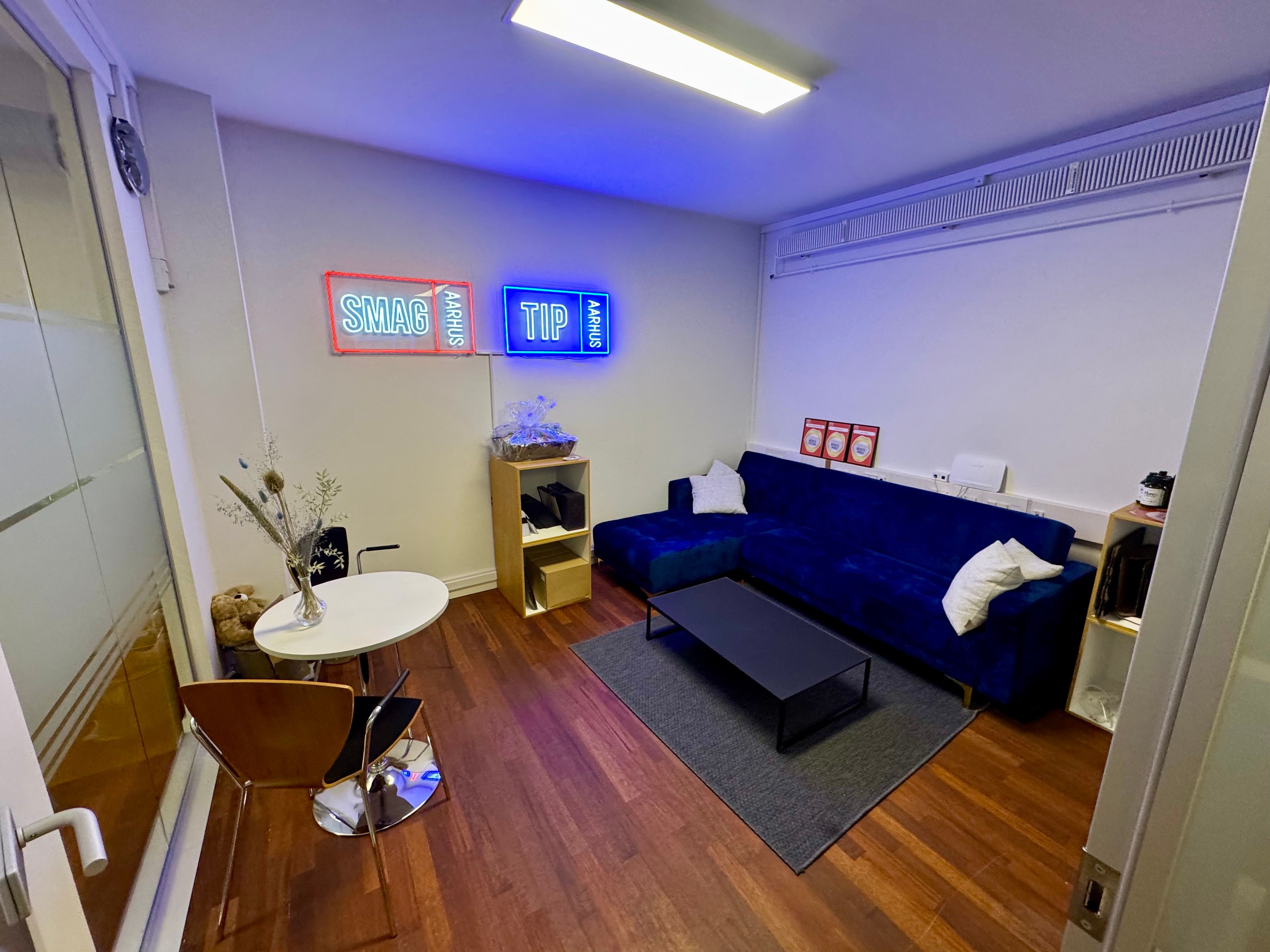 Interiør med møbler og dekorationer, blå sofa, hvid bord, kaffebord og neon skilte med tekst