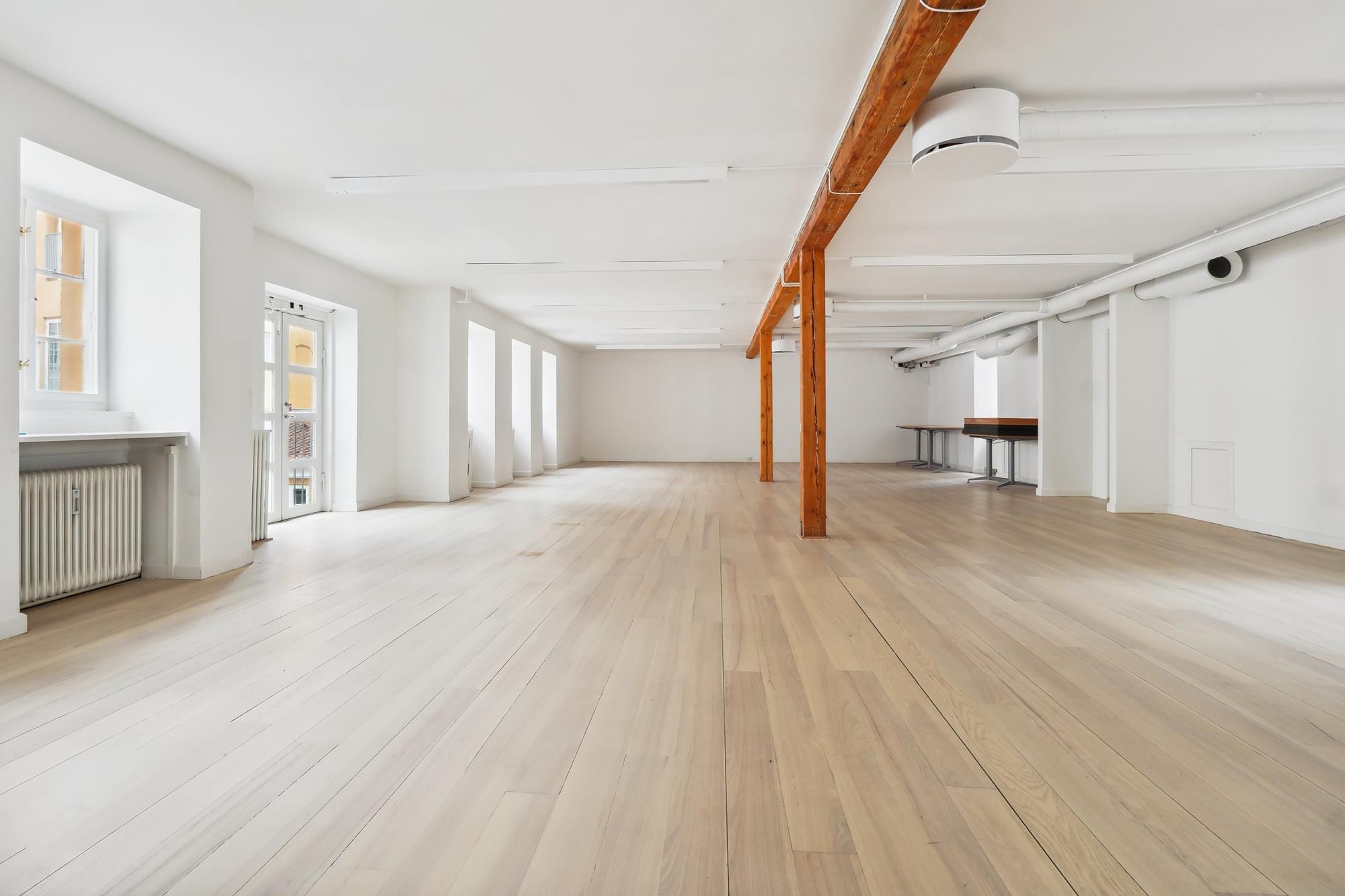 Moderne kontorer med højt loft og lyse trægulve samt åbne vinduer med en integreret køkkenniche