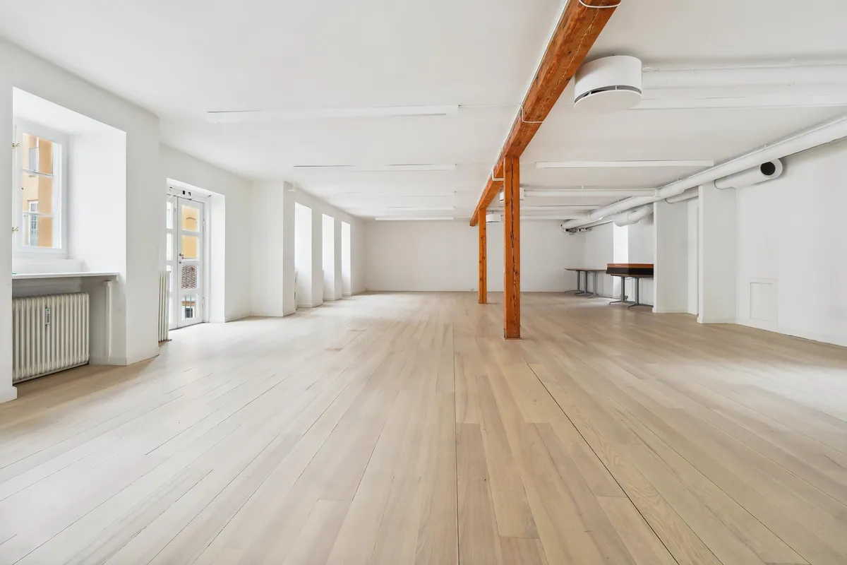 Moderne kontorer med højt loft og lyse trægulve samt åbne vinduer med en integreret køkkenniche