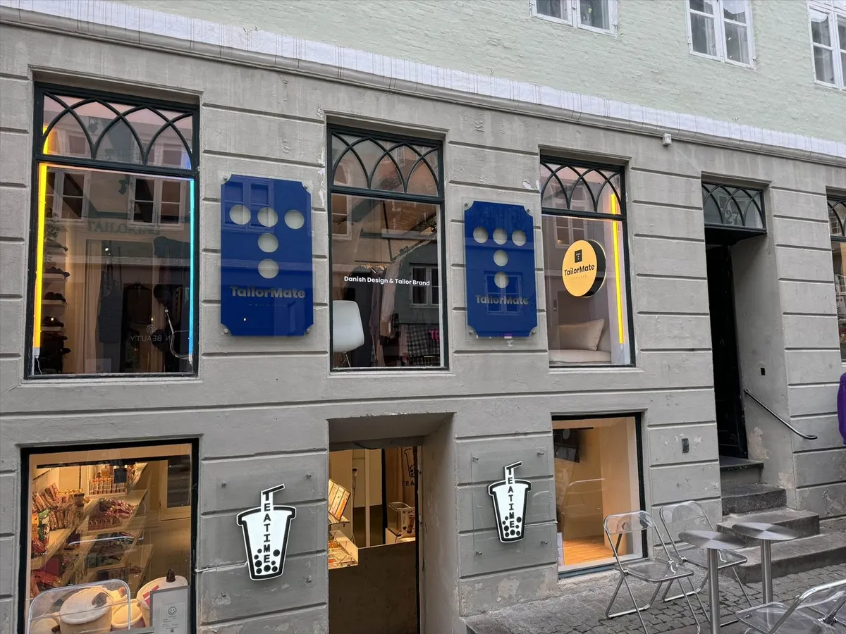 TailorMate butikslokaler med store vinduer og åbent dør og stol og bord udenfor