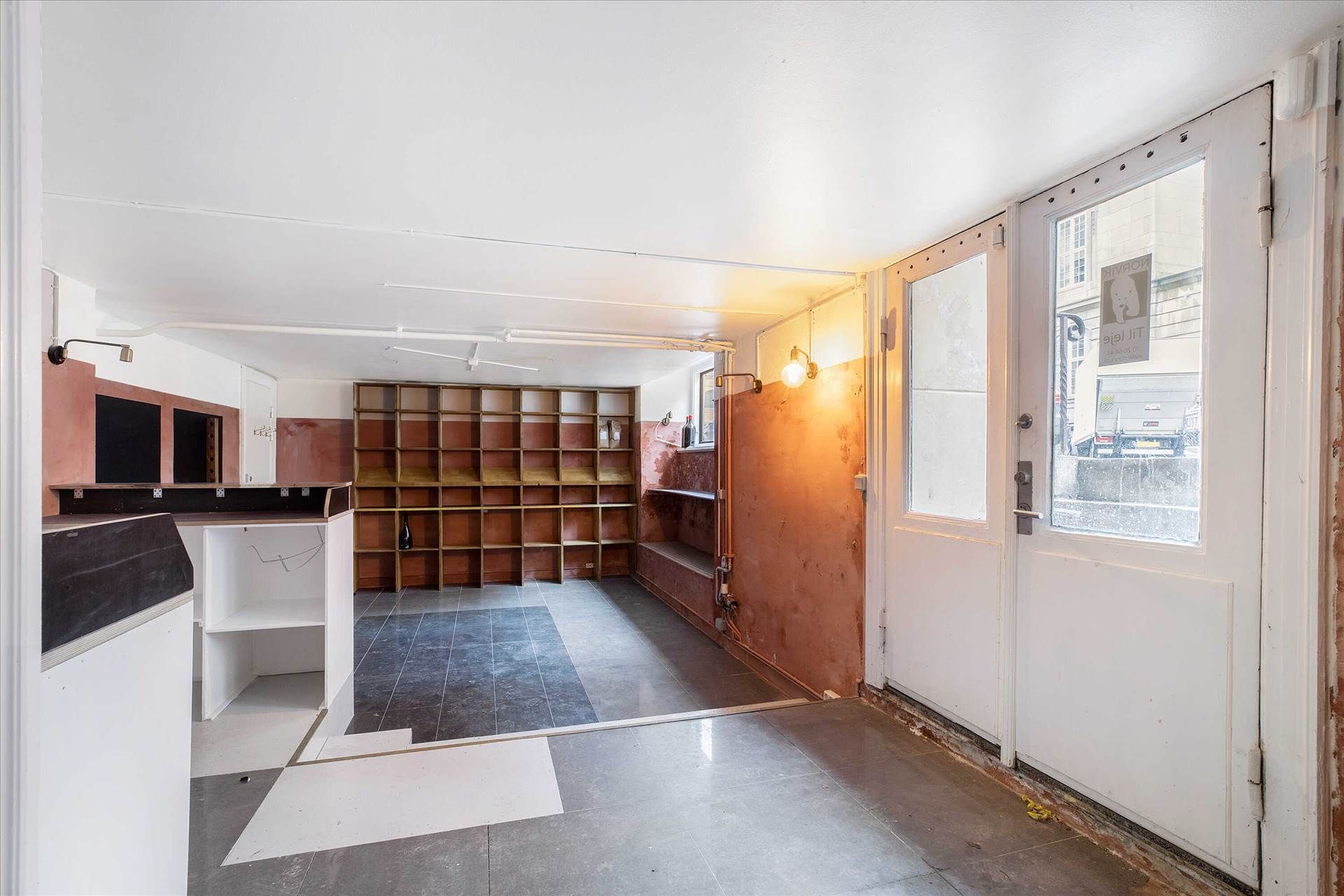 Et køkken med en mur, hvor der er en åben dør og et vindue med et skilt