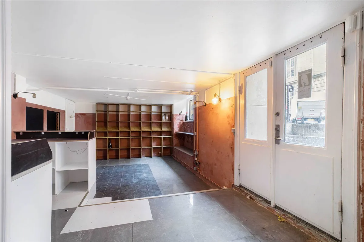 Et køkken med en mur, hvor der er en åben dør og et vindue med et skilt