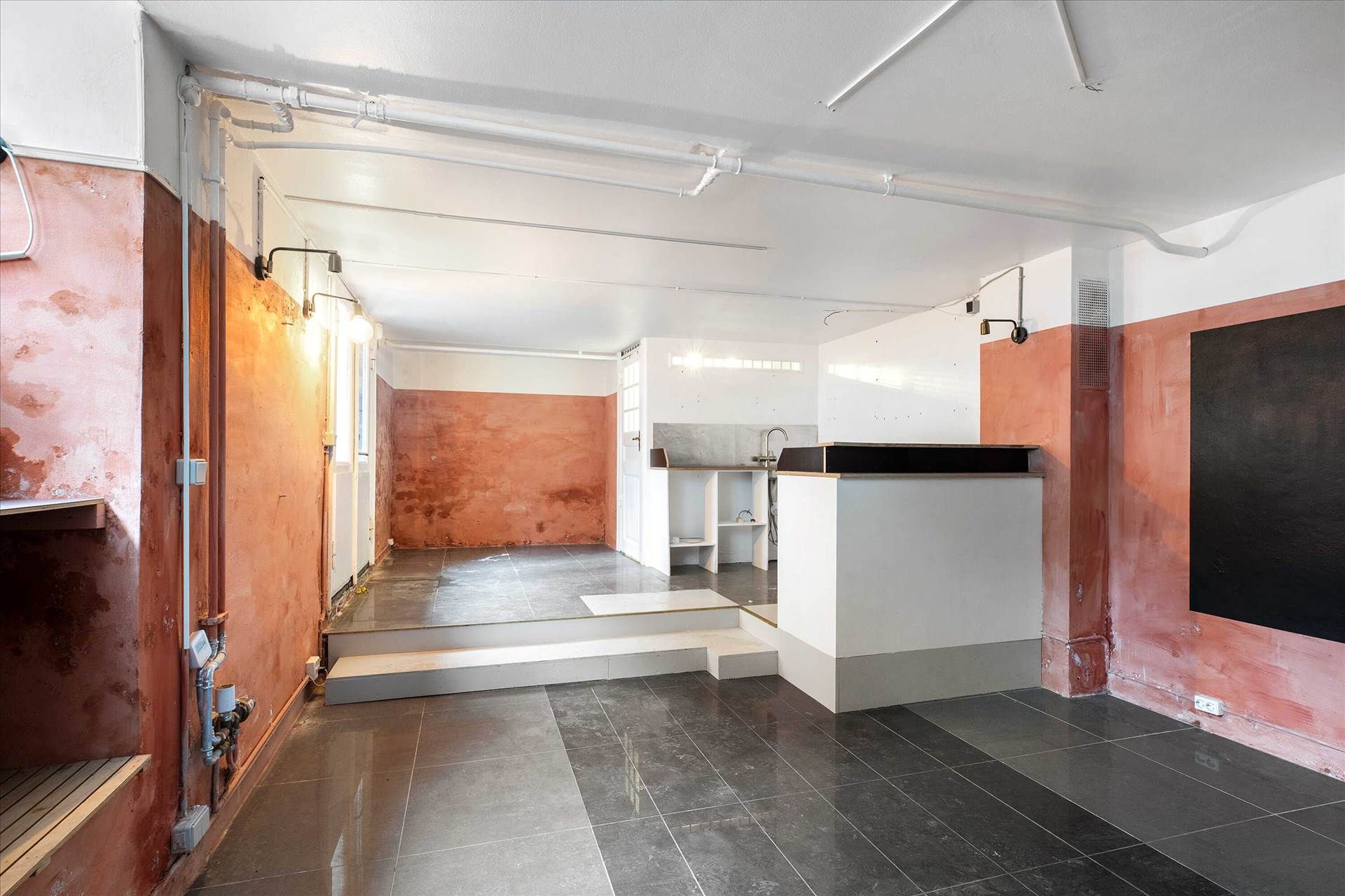 Indvendigt studie med lysegul og rød væg og sort bordplade og gulv med lyse hjørner og loftslampe