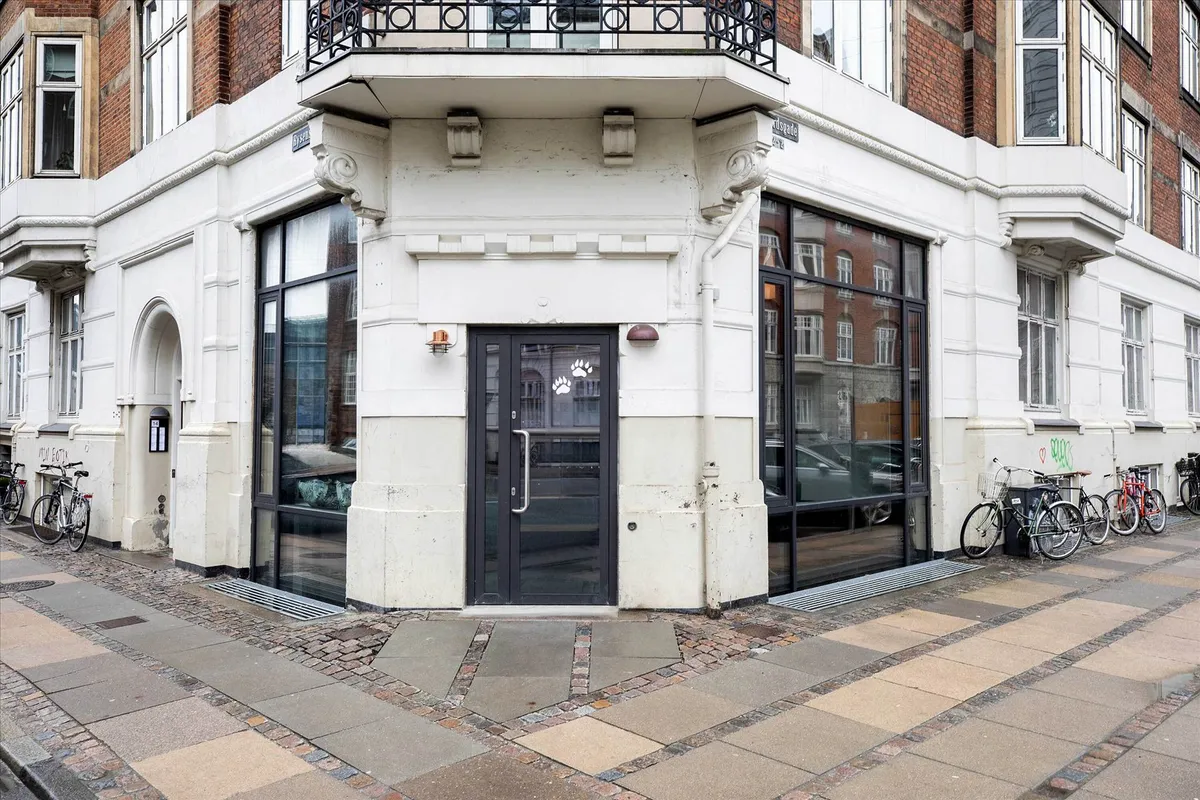 En gård med to høje huse med glasruder og et stort glasdøre med et motiv på døren. To cykler står parkeret på højre side af