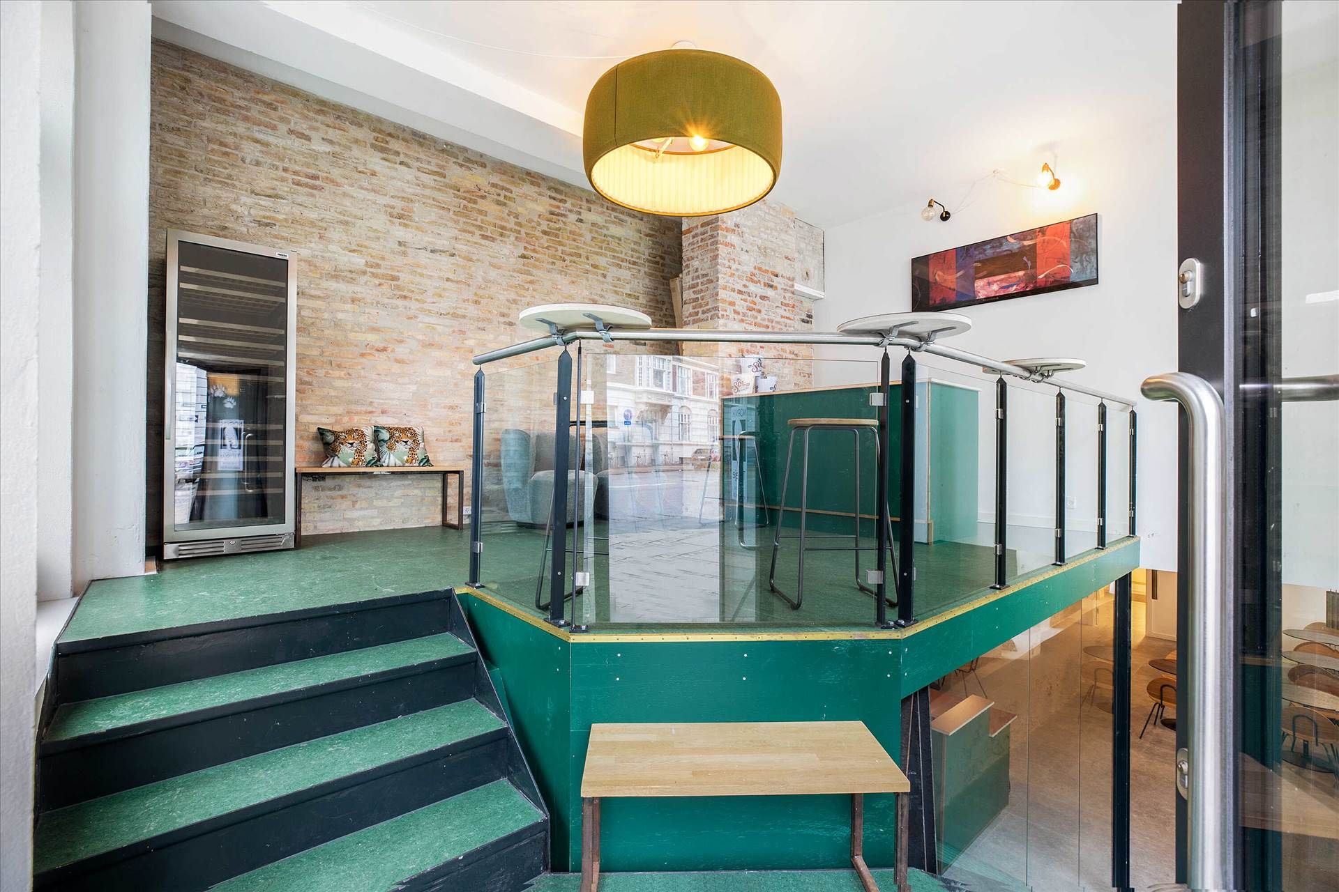 Inde i lejligheden er der et moderne og minimalistisk design med grønne gulve og en glasbalkong med metalrammer og sæder