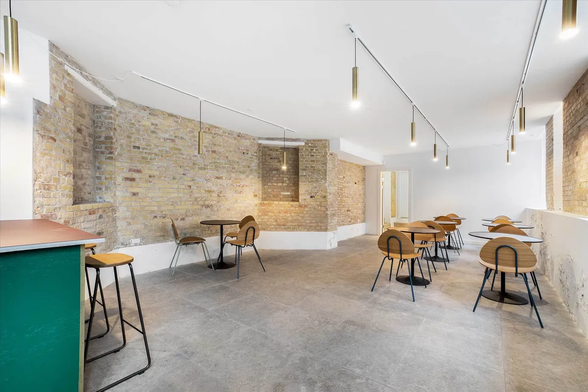 En stor, lyse stue med lysegult loft, gulv og hvide vægge samt lyse træstole og borde